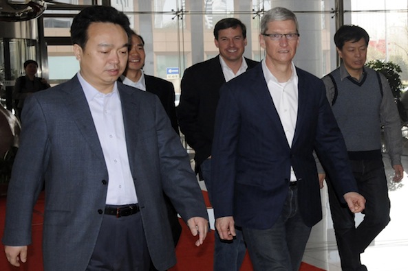 Apple CEO Tim Cook walks with employees as he arrives at the headquarters of China Telecom in Beijing
