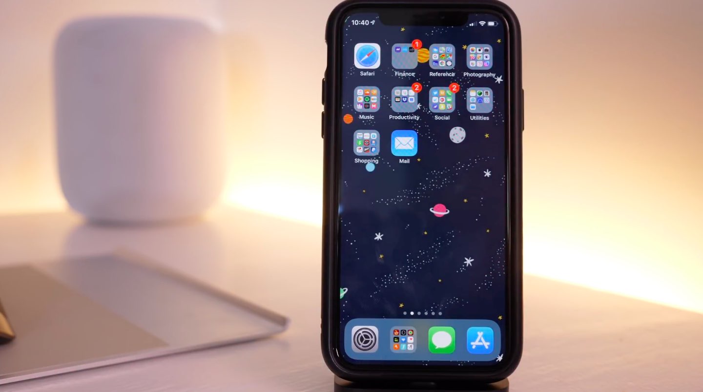Home screen on an iPhone X with a custom space-themed background