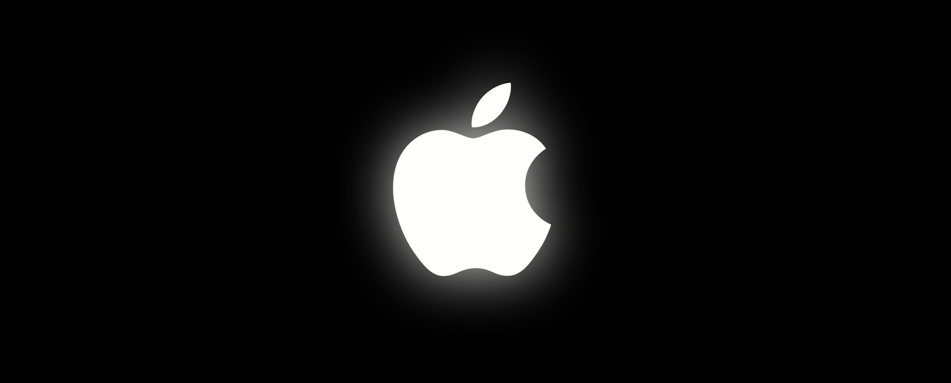 An image showing a slightly glowing whit Apple logo set against a dark background