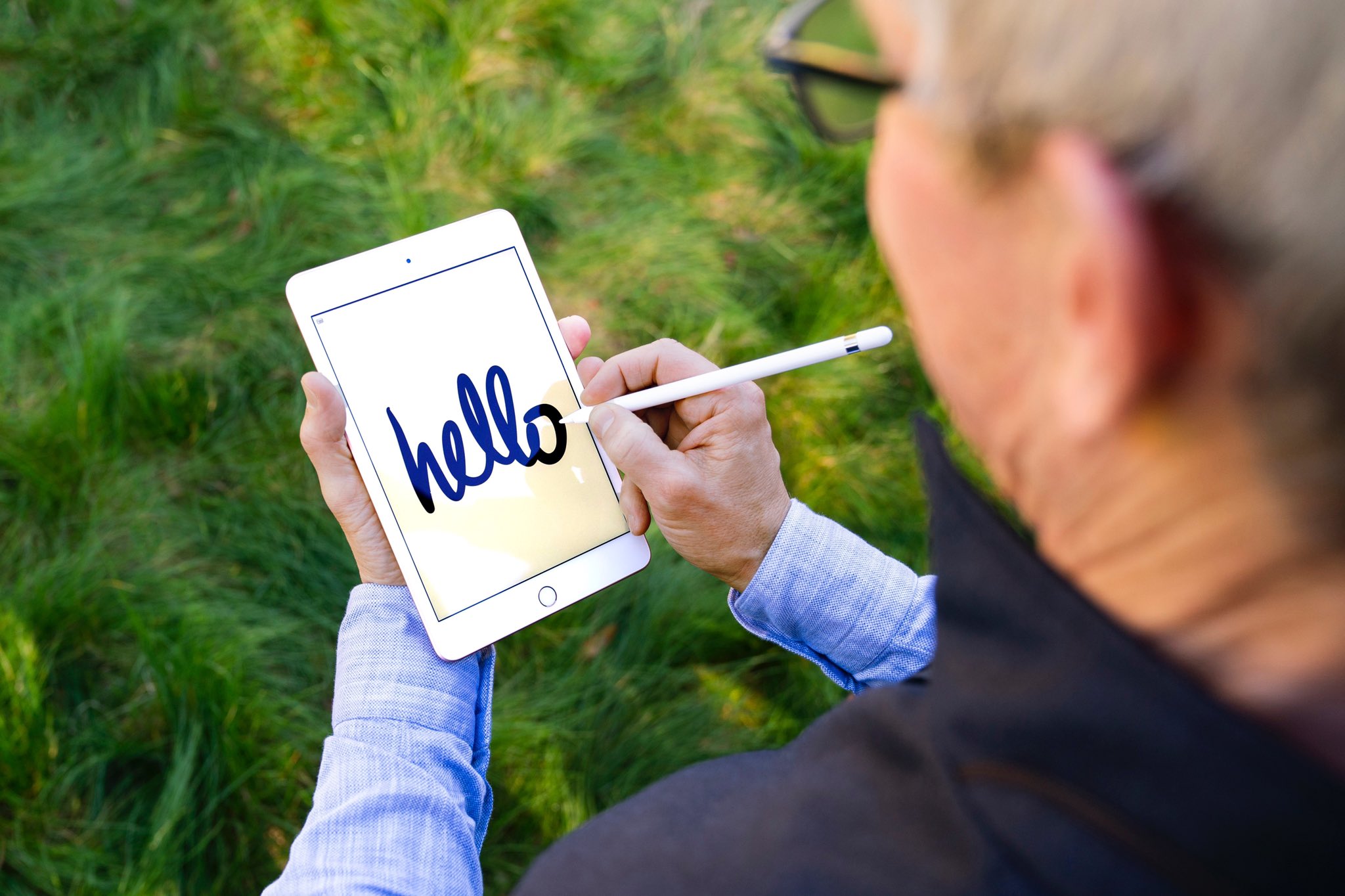 Apple's press photo showing CEO Tim Cook drawing the word "hello" with his Apple Pencil on iPad mini