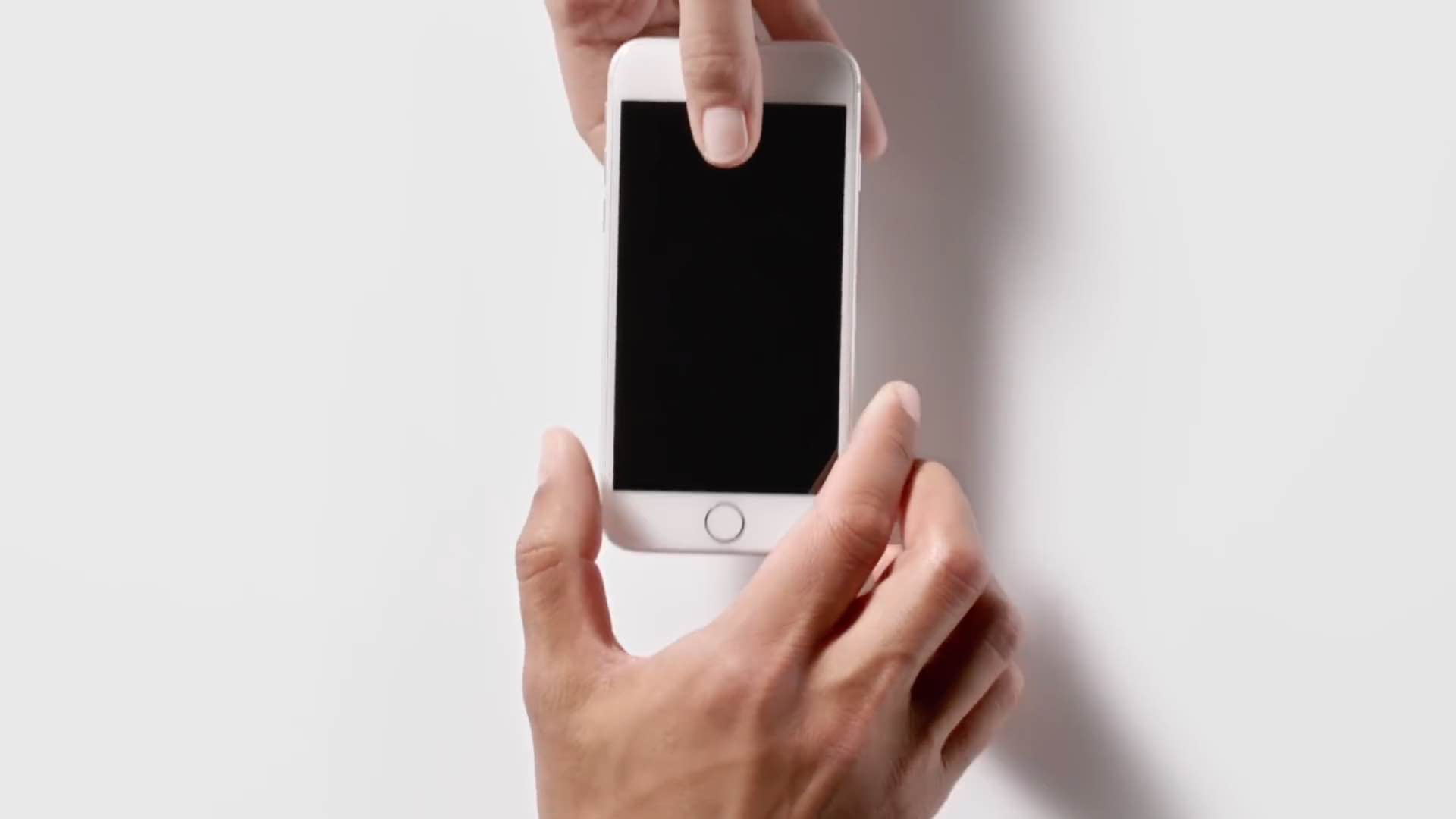 A scene from Apple's ad showing a male hand handing an iPhone 5s over to another male's hand