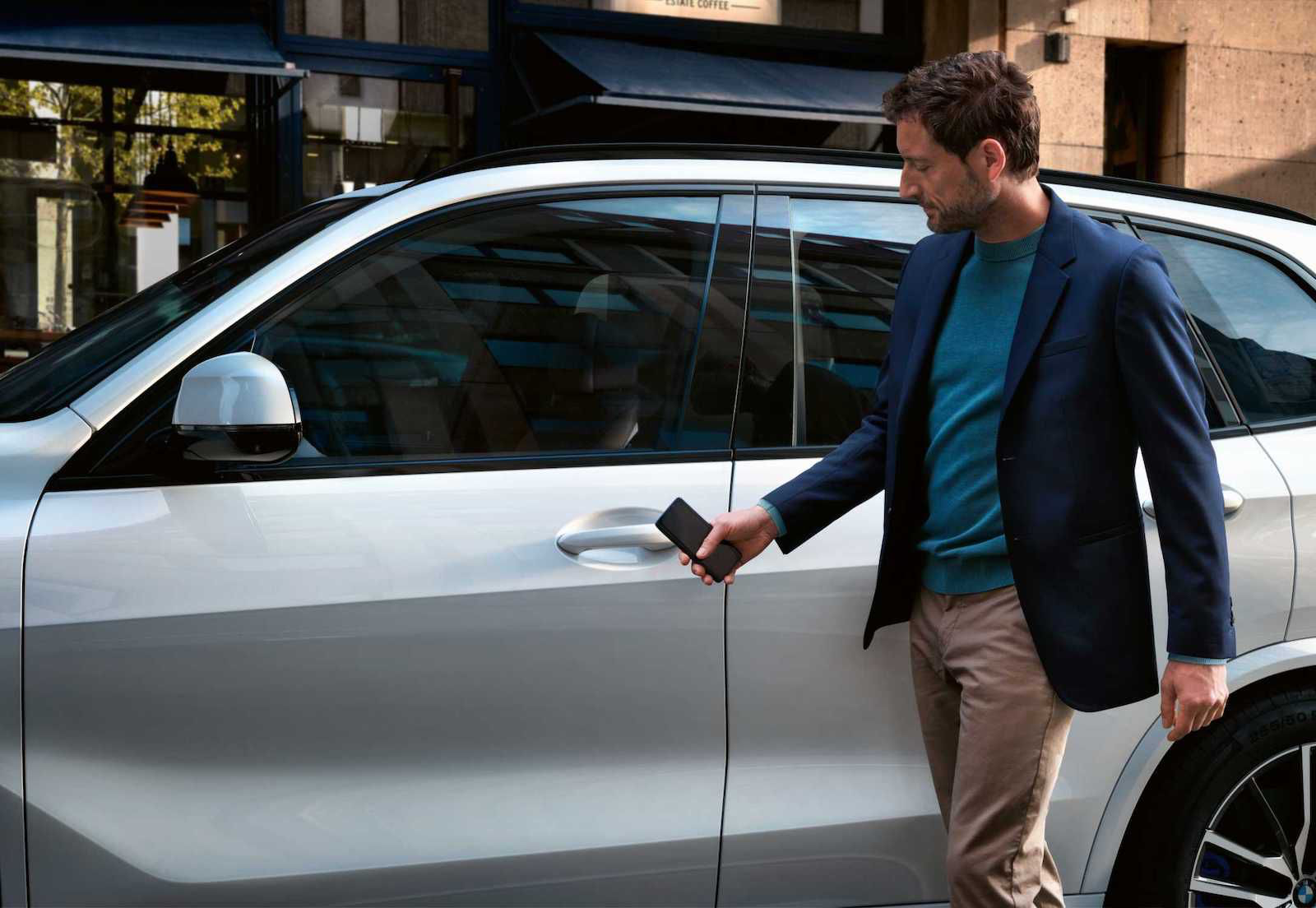Ein Apple-Marketingbild, das die Verwendung der CarKe-Funktion zum Entsperren eines BMW-Autos mit einem iPhone zeigt