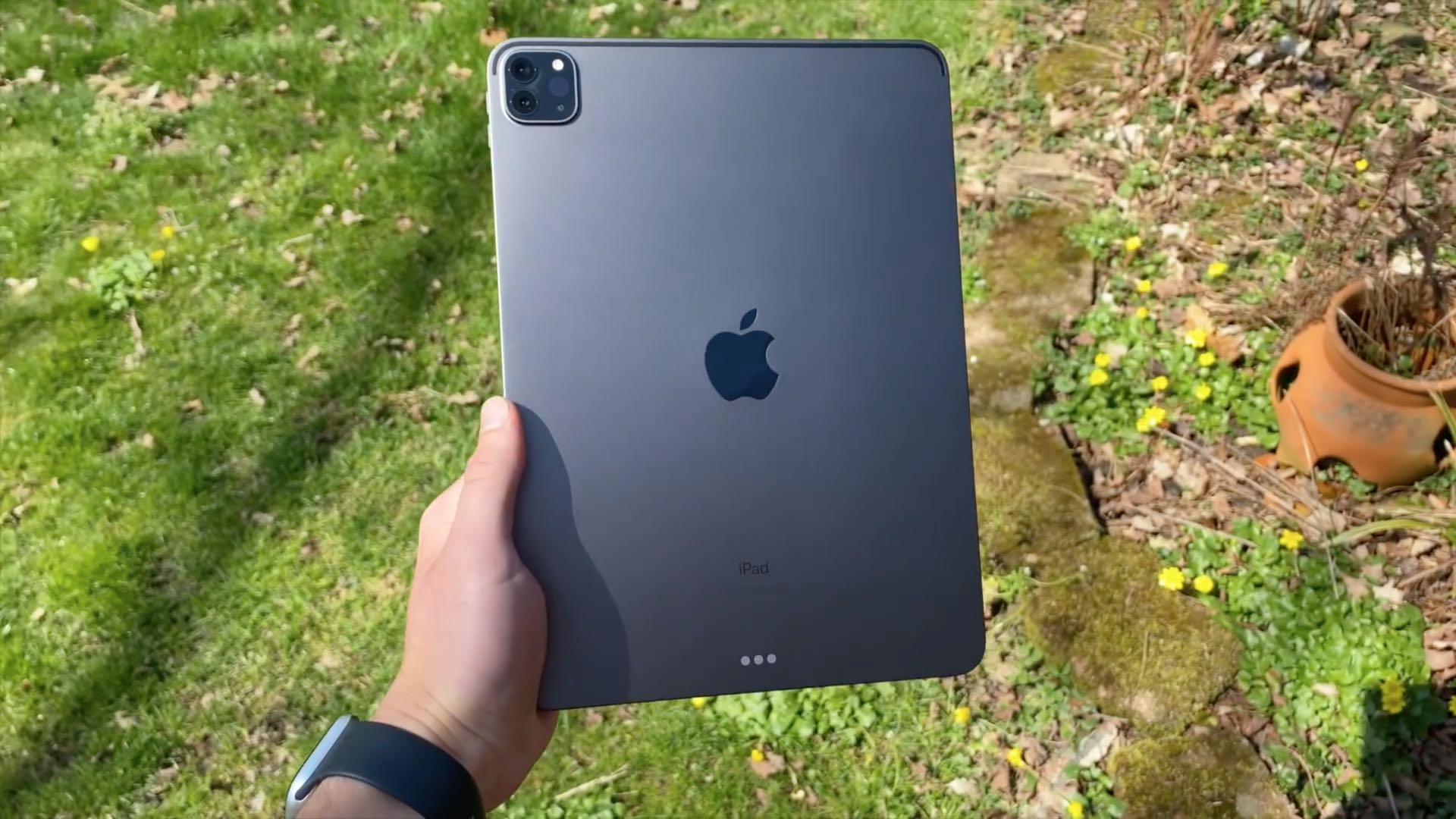 iPad Pro being held by a male's hand hand outside in a park