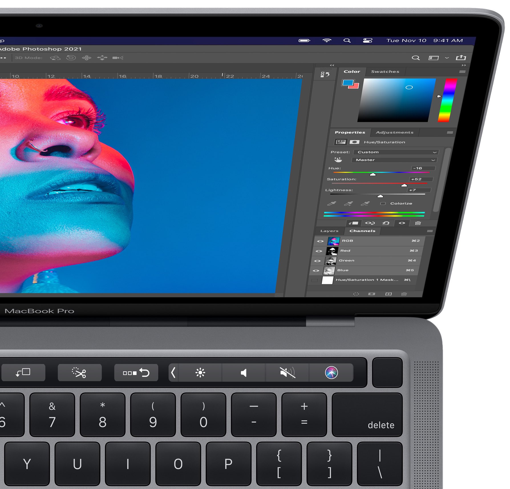A close up of the right half of the Apple M1 MacBook Pro notebook with Adobe Photoshop show on the display and related Touch Bar shortcuts