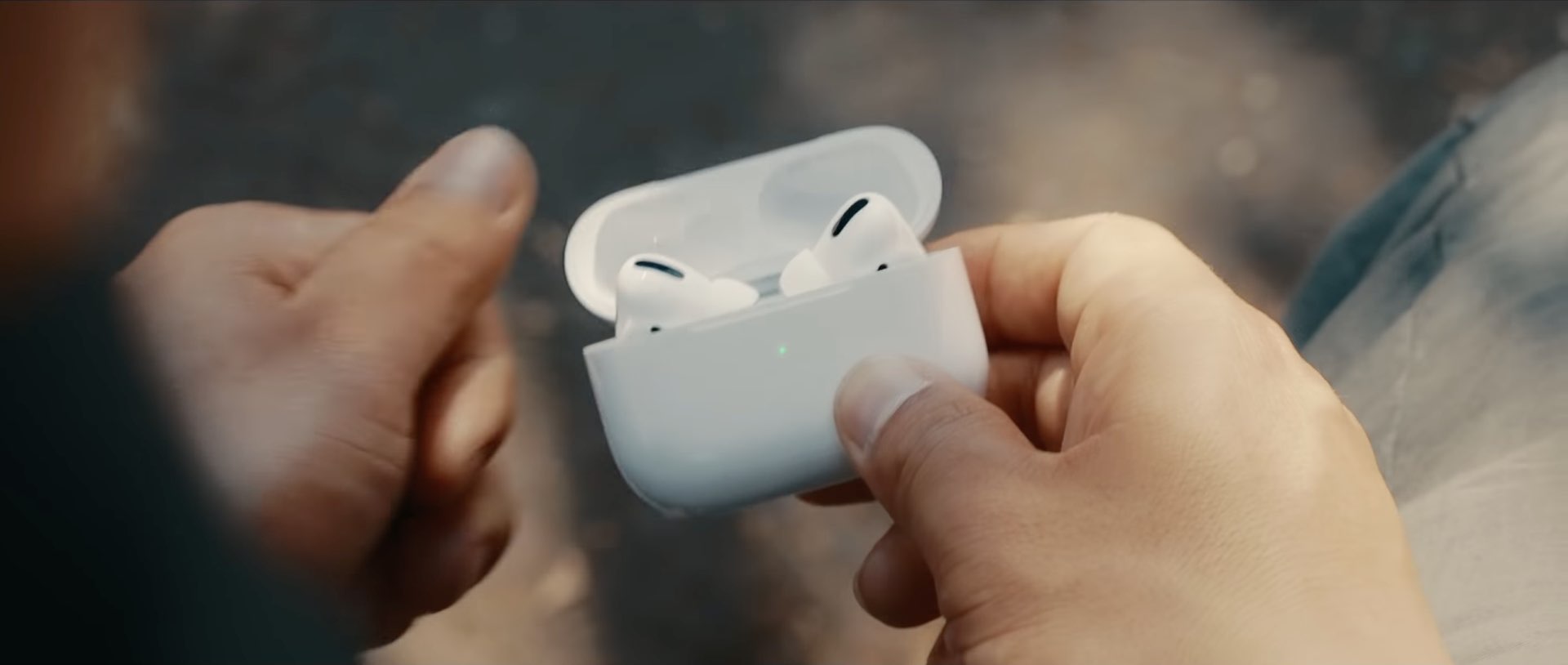 A still from Apple's ad showing a you man's hand holding an open AirPods Pro charge case with the earbuds inside