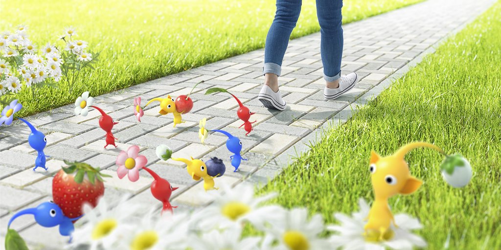 A promotional image for the Pikmin augmented reality game from Nintendo and Niantic showing a person walking on a colorful cobblestone road pavement