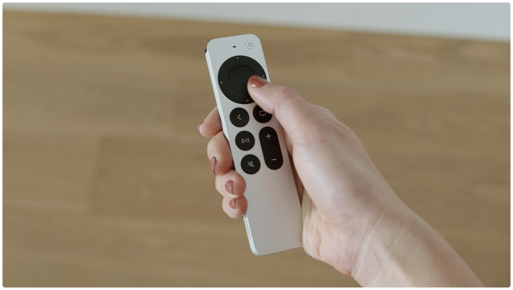 Apple's promotional image depicting a female hand holding the redesigned Siri Remote that ships with the second-generation Apple TV 4K