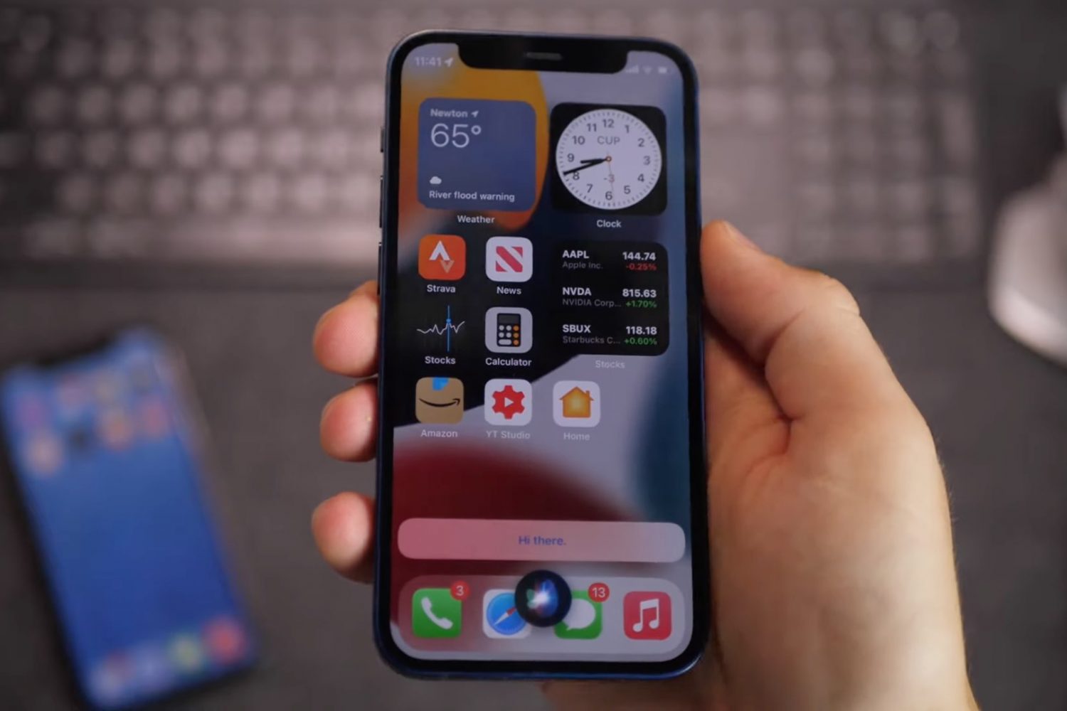 Une image montrant un iPhone 12 tenu en main avec l'orbe lumineux en bas indiquant la fonctionnalité Siri hors ligne