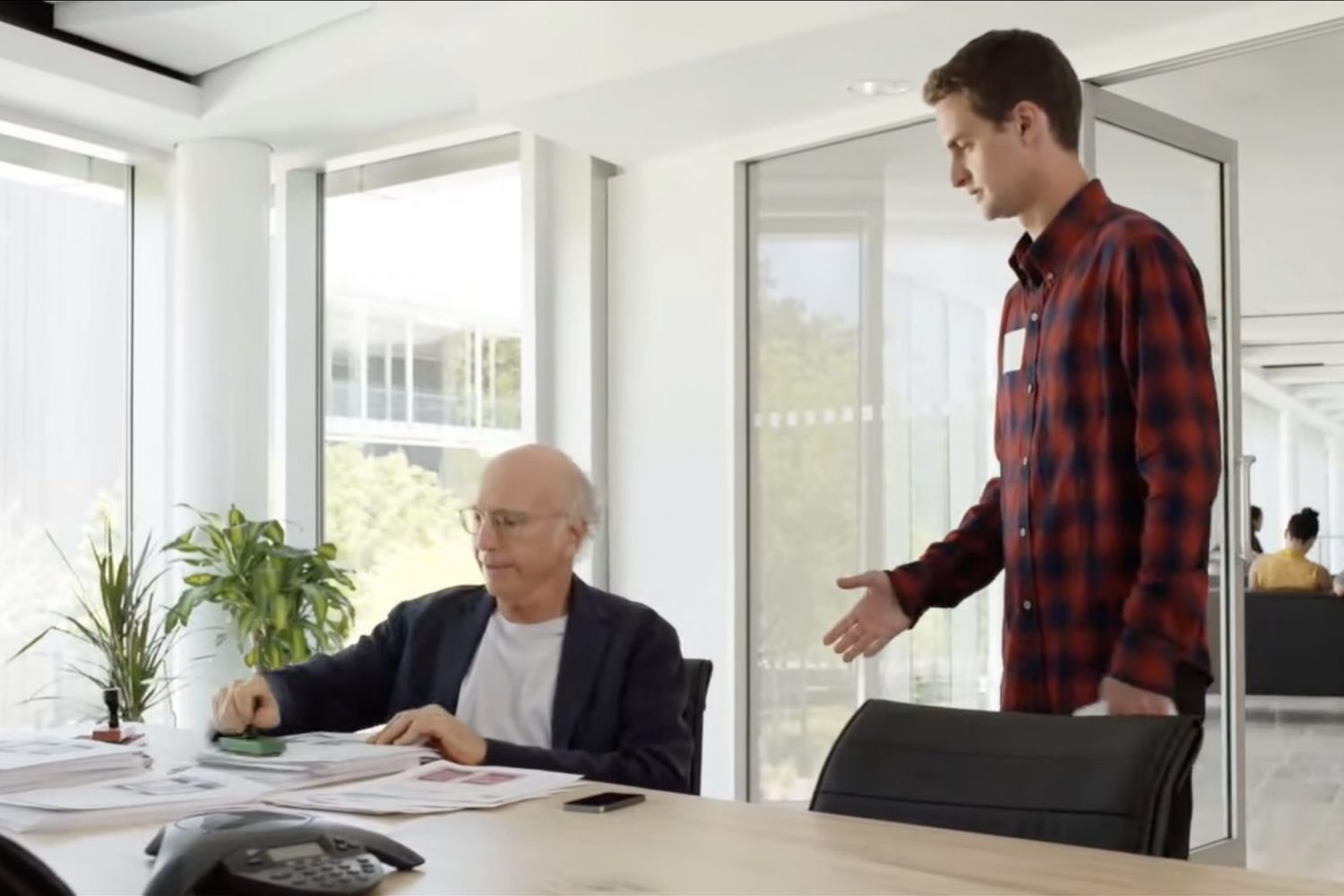 A still from Apple's unaired WWDC14 opening film showing Larry David as an app approval specialist and Snapchat founder Evan Spiegel