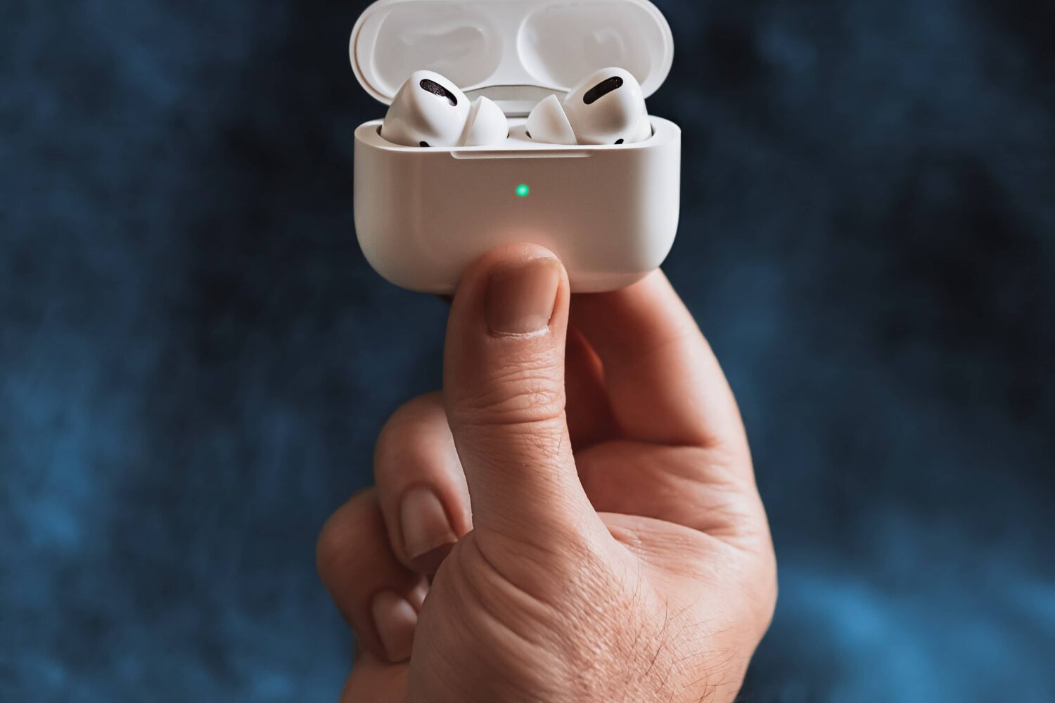 A male hand holding a charge case for AirPods Pro with the earbuds inside and the lid open