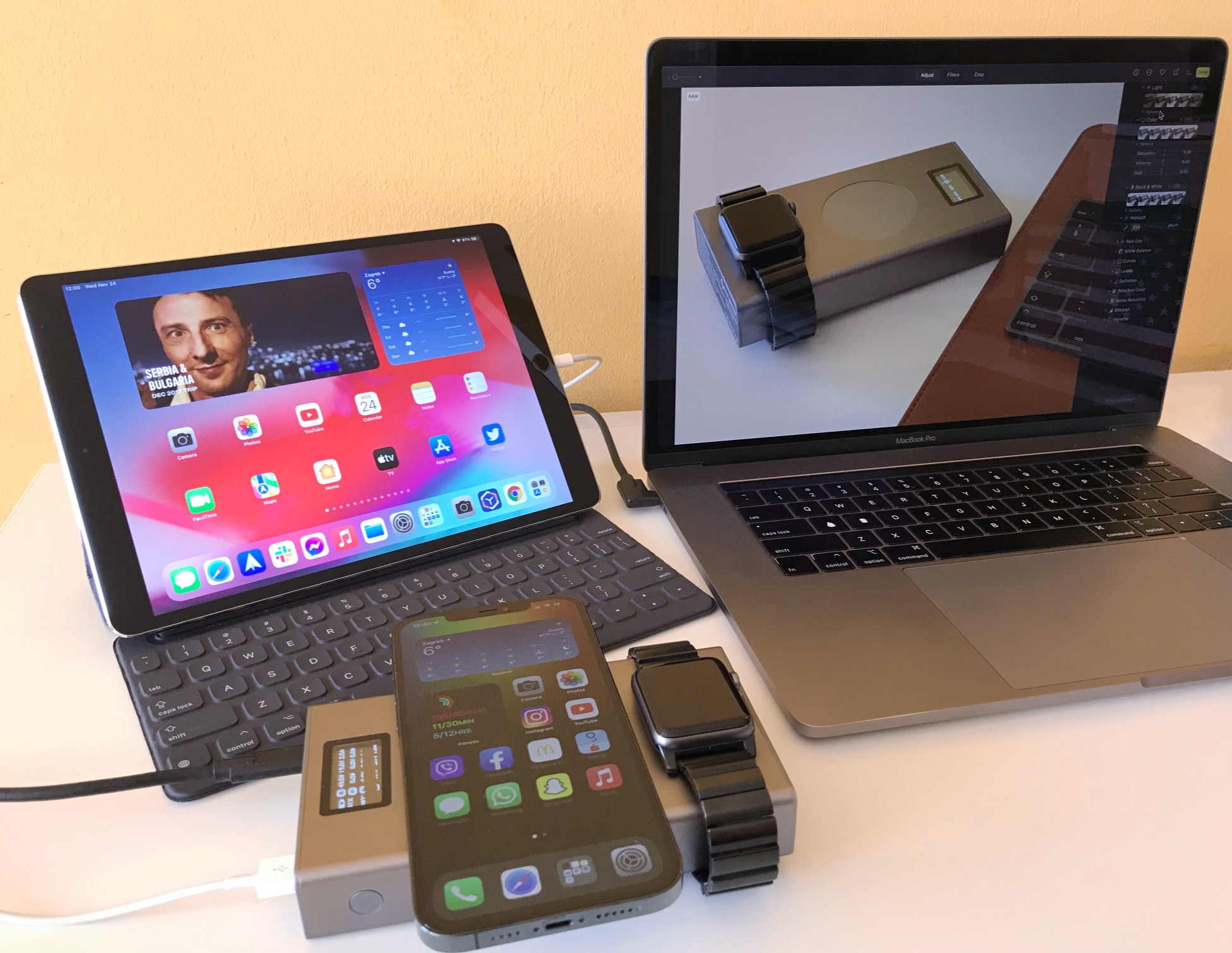 A photograph showing a workdesk with Chargeasap's Flash Pro Plus portable power bank wirelessly charging Apple Watch and iPhone 12 Pro Max while connected to iPad Pro and MacBook Pro