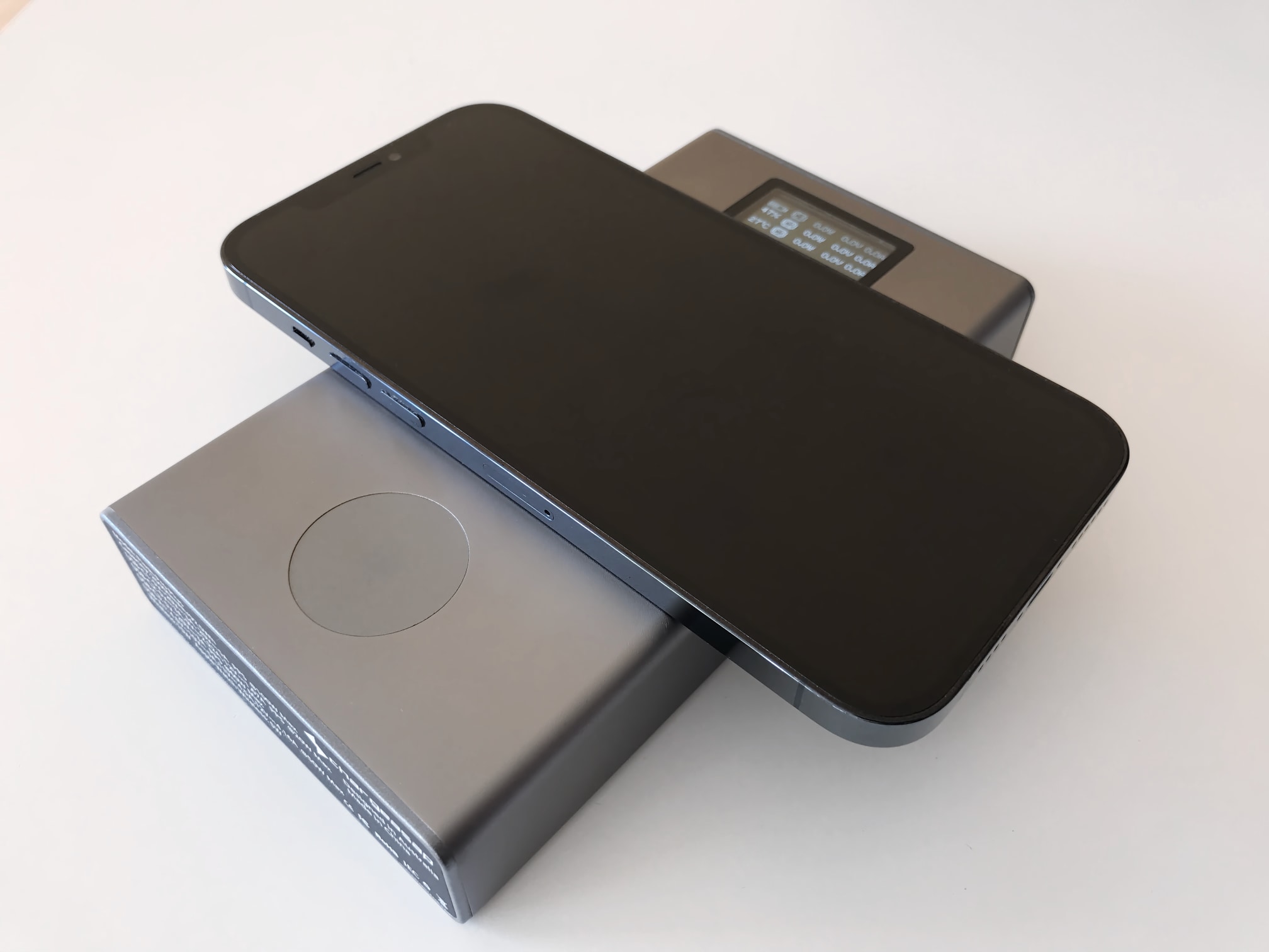 A photograph showing an isometric view of iPhone 12 Pro Max resting and wirelessly charging on the MagSafe pad of Chargeasap's Flash Pro Plus portable power bank