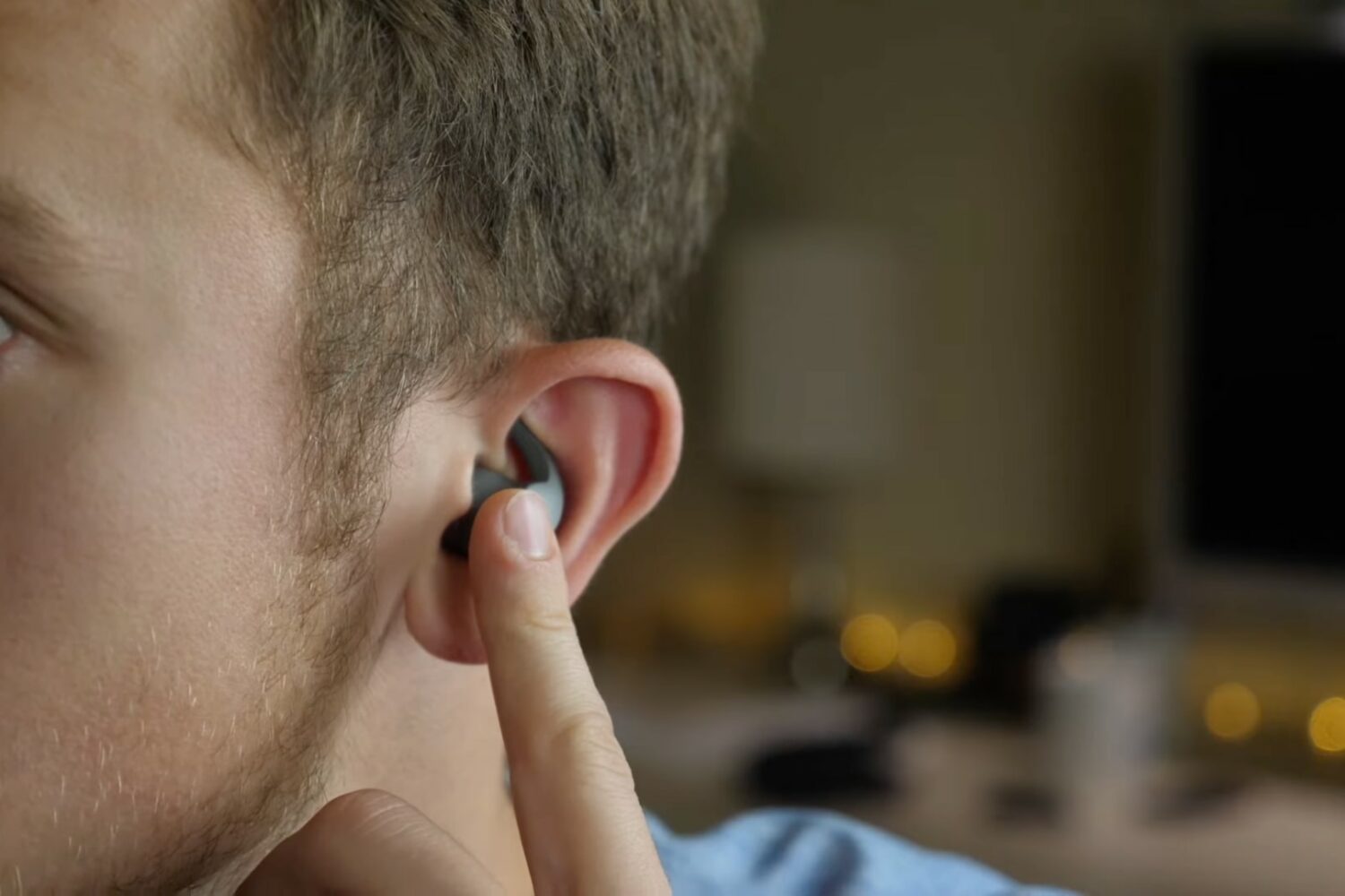 A closeup photo showing the right half of a young male's face wit a Beats Fit Pro earbud fitted inside their ear