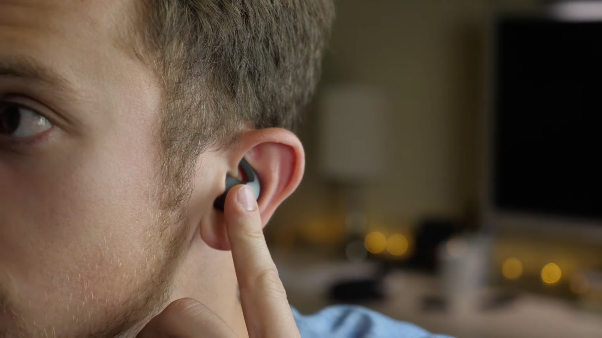 A closeup photo showing the right half of a young male's face wit a Beats Fit Pro earbud fitted inside their ear