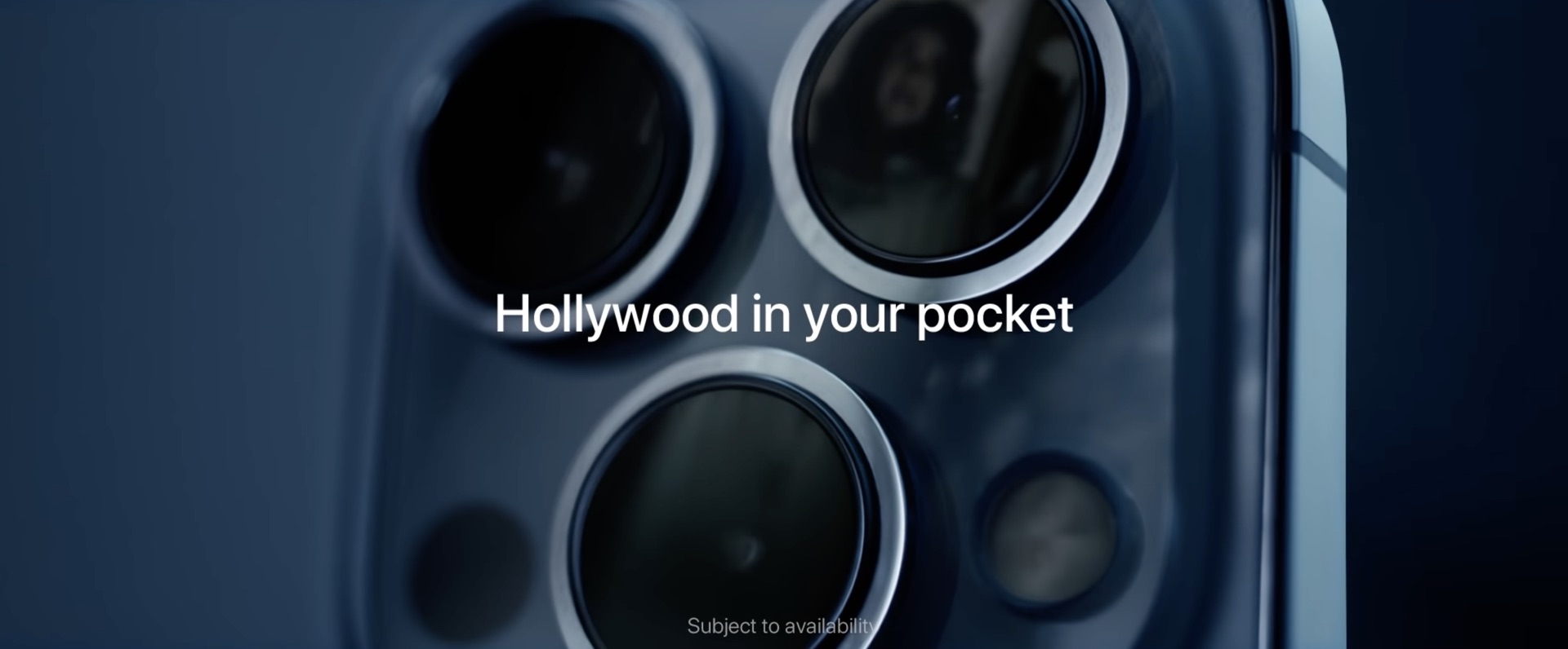 A still from Apple's ad promoting better low-light sensitivity on the iPhone 13 Pro camera. the image shows the triple-leans rear camera system with a woman's reflection in one of the lenses and the tagline "Hollywood in your pocket"