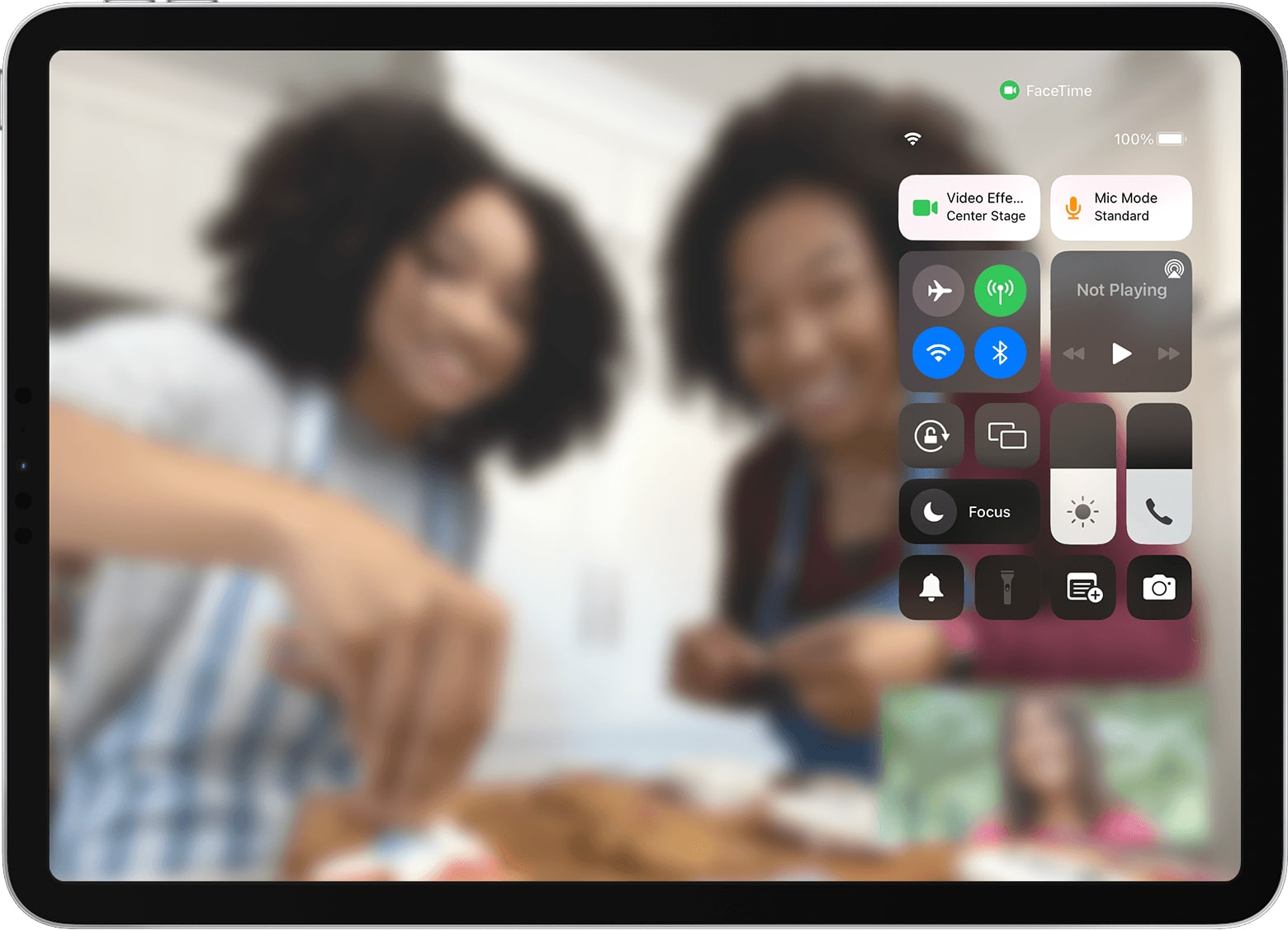Apple's marketing image showing the iOS 15 Control Center overlay on iPad Pro with the Center Stage camera feature turned on, and a blurred FaceTime video call in the background 