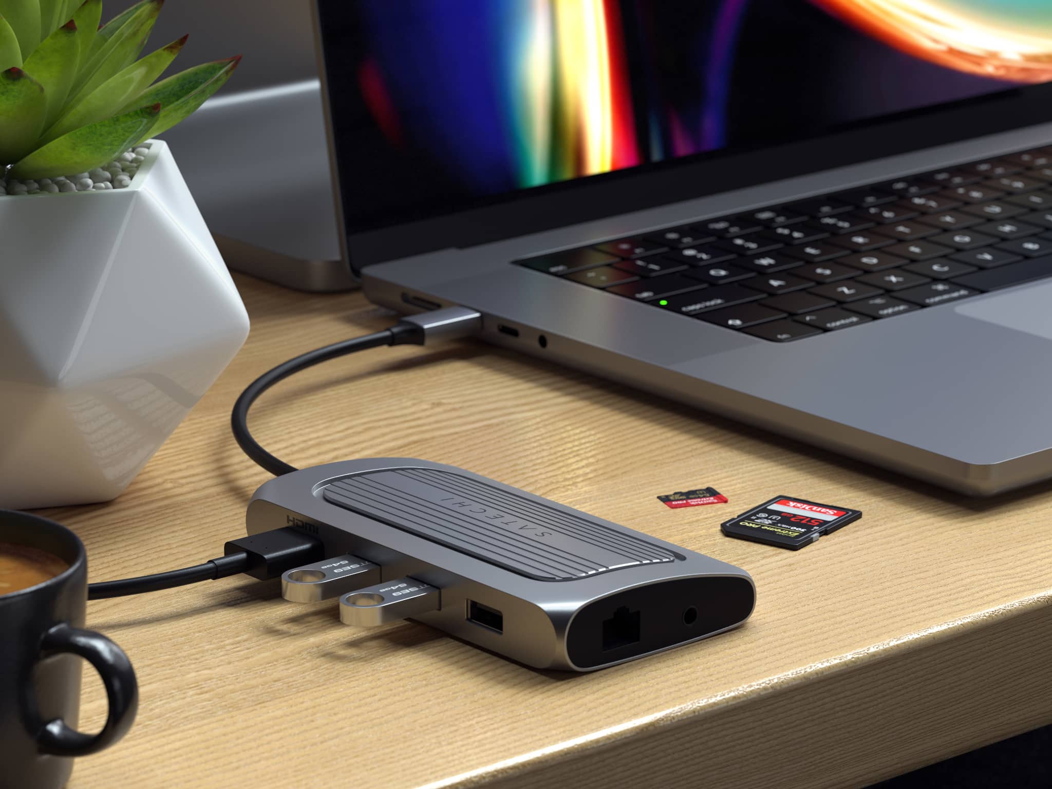 A lifestyle image showing Satechi's USB-4 Multiport Adapter connected to a 16-inch MacBook Pro