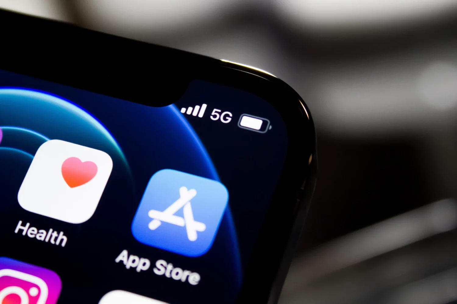 A close-up photograph showing a part of an iPhone display with a focus on the App Store icon in the top right corner