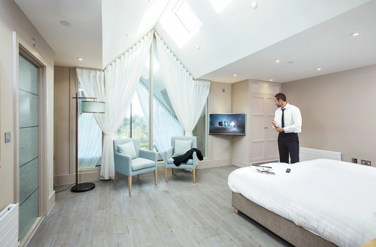 A lifestyle image showing a businessman in a hotel room watching Apple TV+ on a Philips MediaSuite hospitality television set