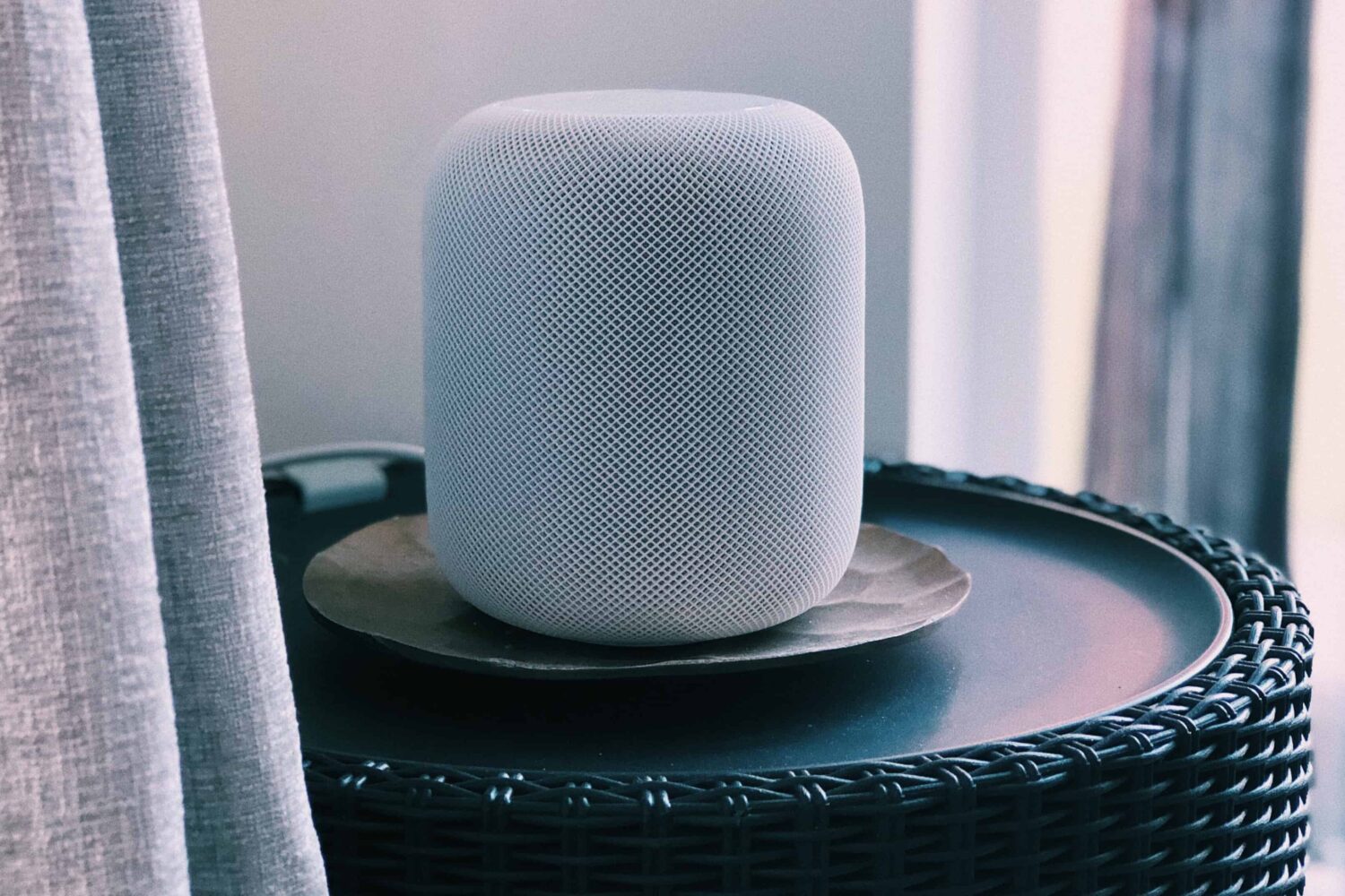 A silver version of Apple's full-size HomePod wireless speaker is shown sitting on a table in this photo from Unsplash