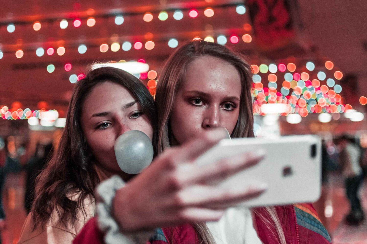 Two female friends are taking a selfie with an iPhone 13 in this photograph from Unsplash