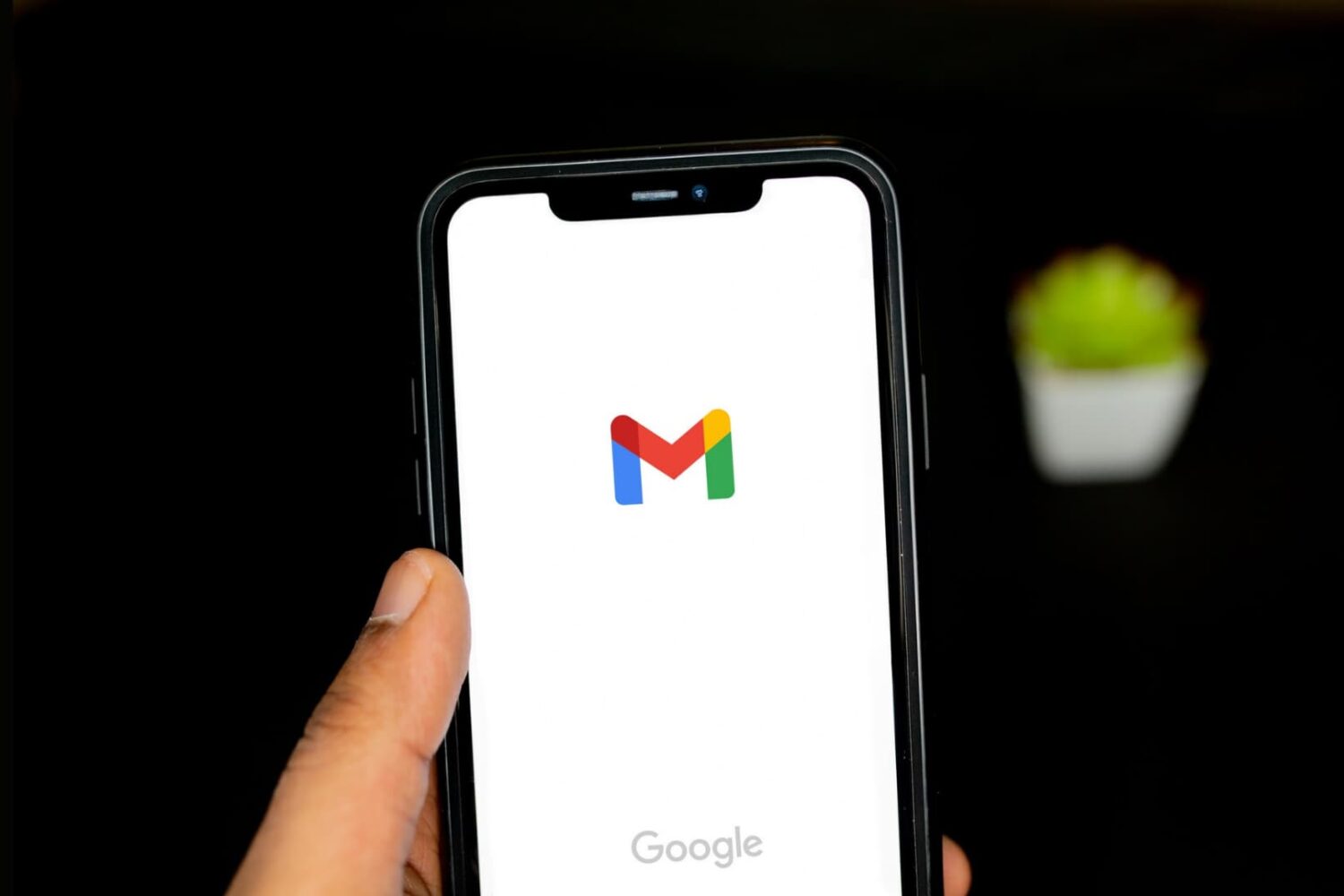 A hand holding iPhone with Gmail logo on the screen