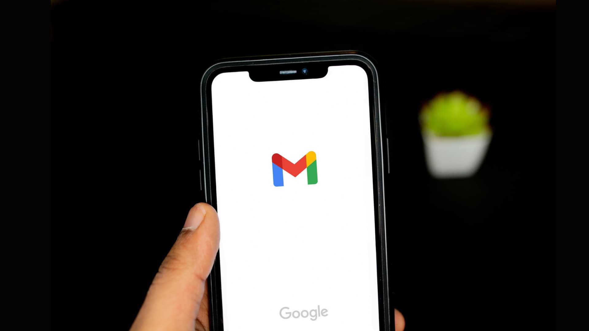 A hand holding iPhone with Gmail logo on the screen