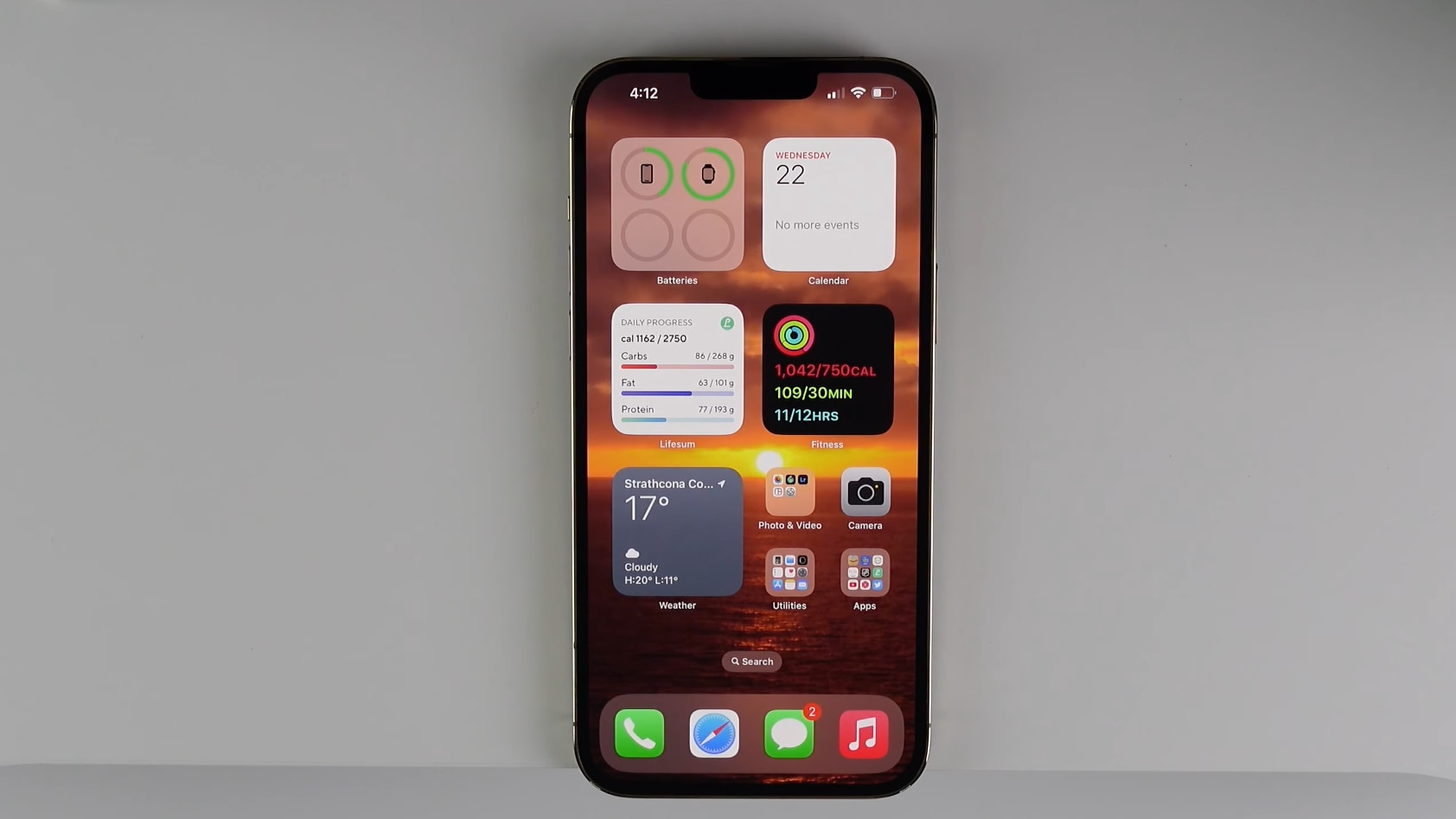 An iPhone with a bunch of widgets, apps and folders displayed on the home screen