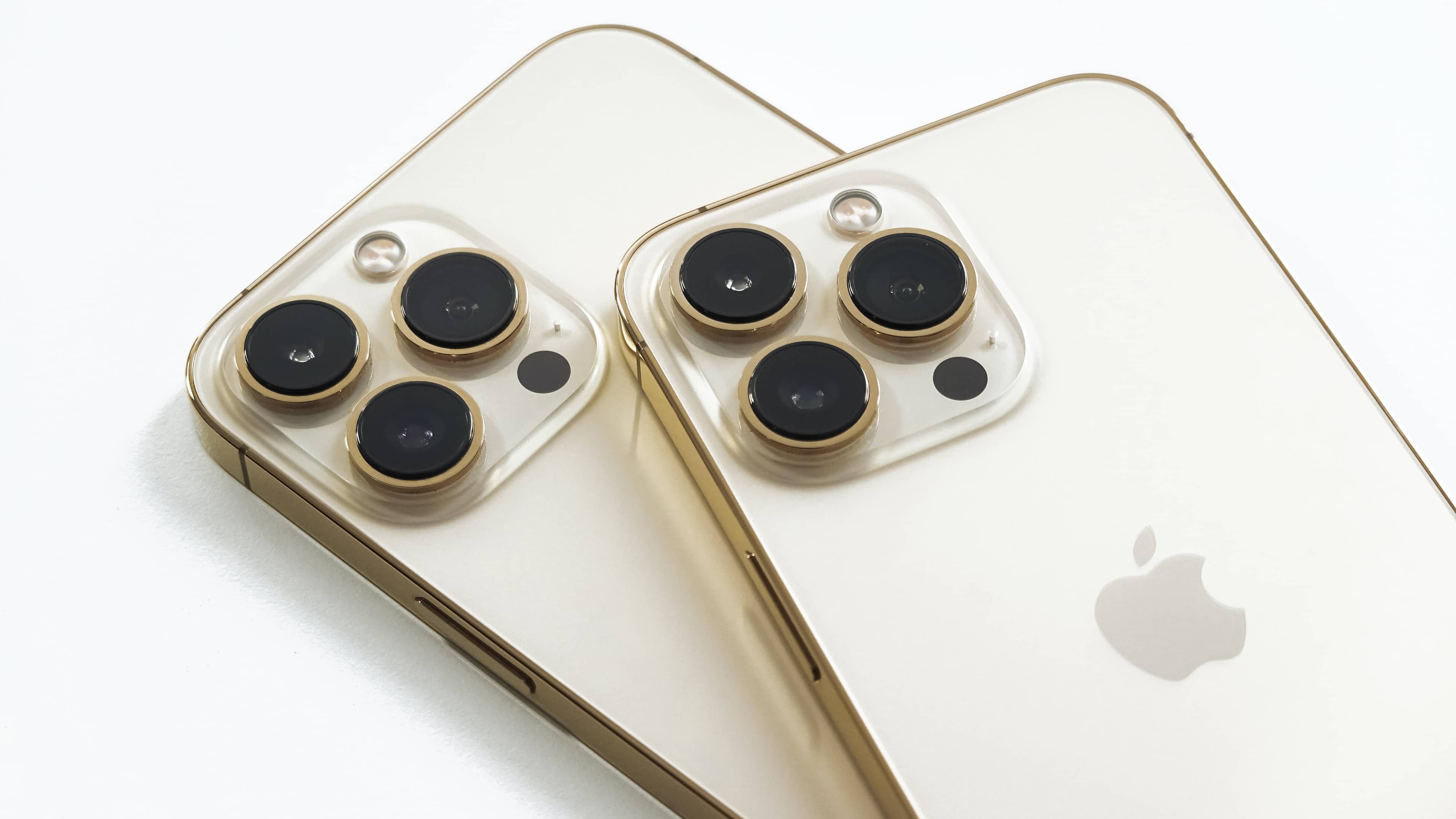 iPhone 13 Pro and iPhone 13 Pro Max laid facedown, showcasing their triple cameras on the back