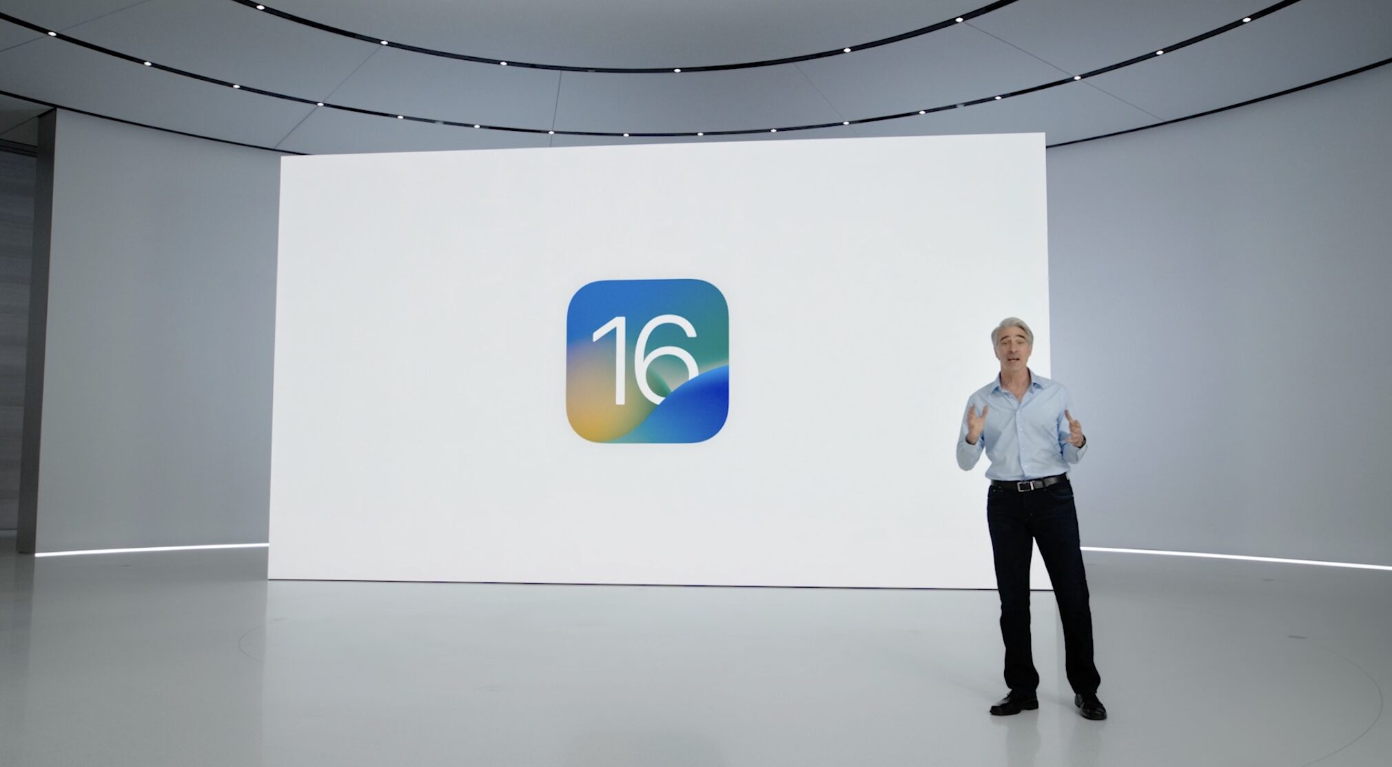 A scene from the June 6 WWDC 2022 keynote, with Apple's software chief Craig Federighi standing in front of a slide showcasing the iOS 16 icon