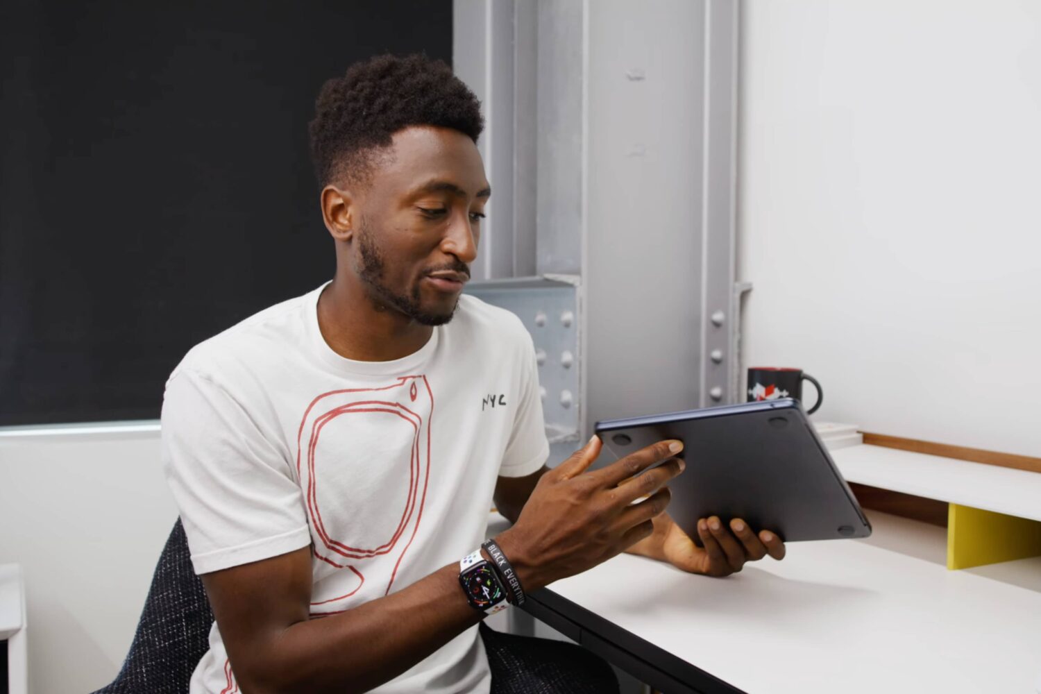 YouTuber Marques Brownlee is in his studio, holding Apple's MacBook Air laptop in the Midnight color and inspecting the nicks around USB-C ports