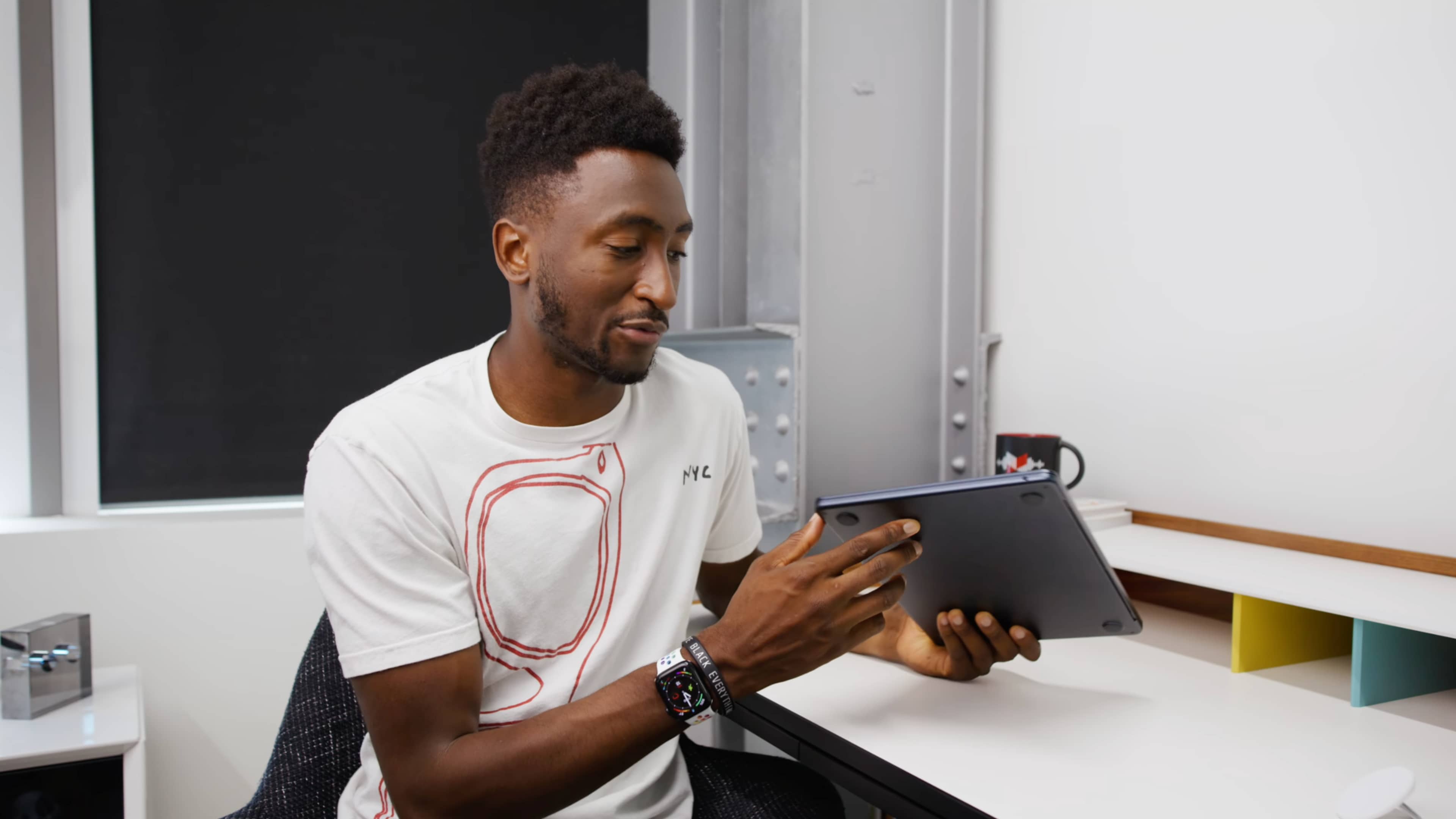 YouTuber Marques Brownlee is in his studio, holding Apple's MacBook Air laptop in the Midnight color and inspecting the nicks around USB-C ports