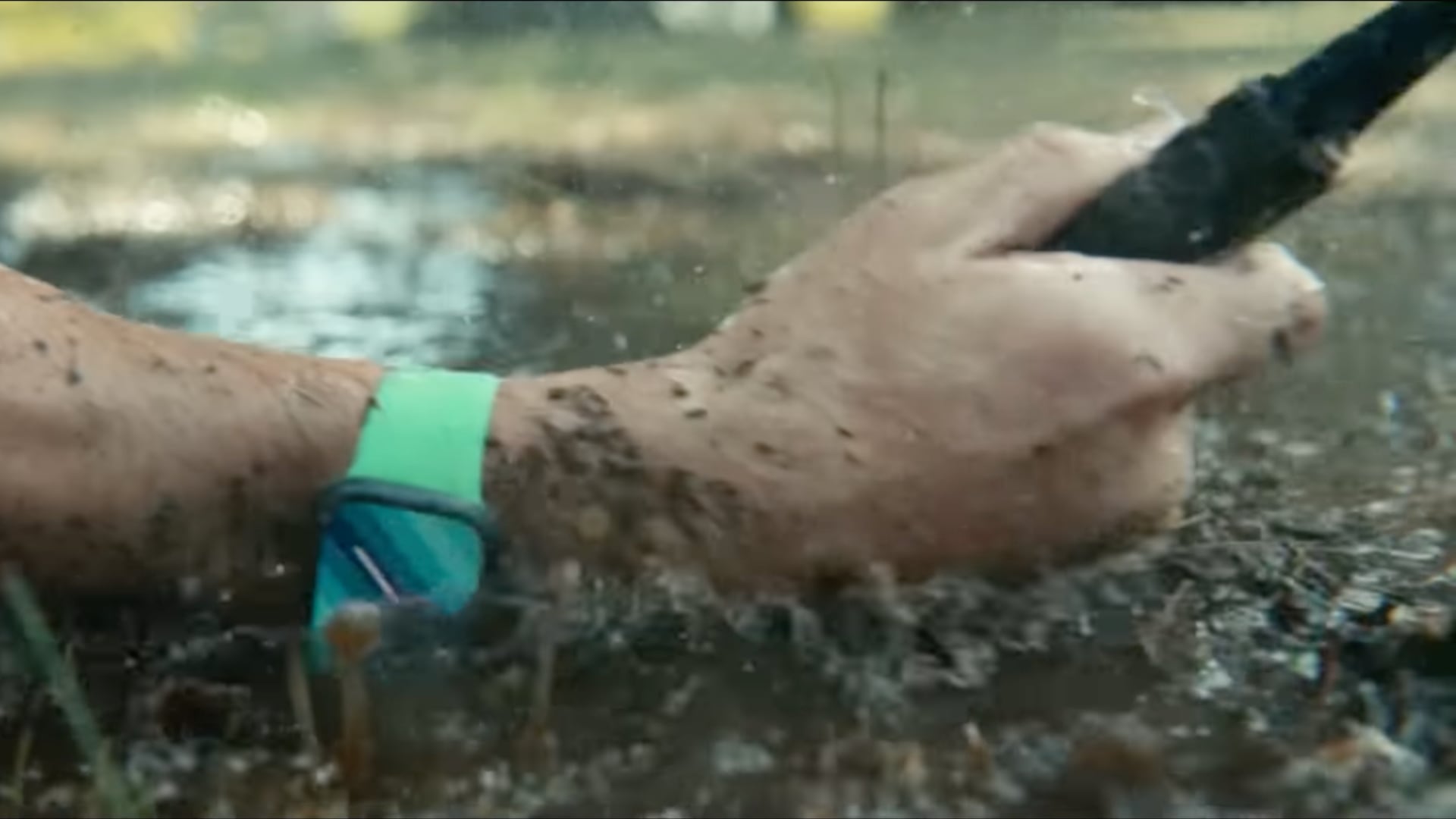 A closeup of a tennis player's forearm hitting the mud while wearing an Apple Watch Series 7 on their wrist and squeezing a racket in their hand