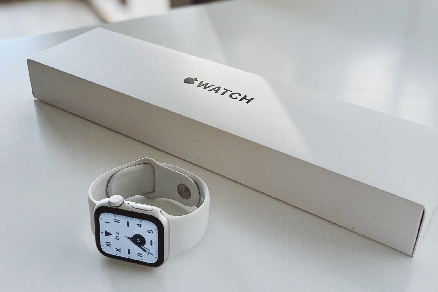 Apple Watch Series 7 rating on its side on a white table alongside its packaging
