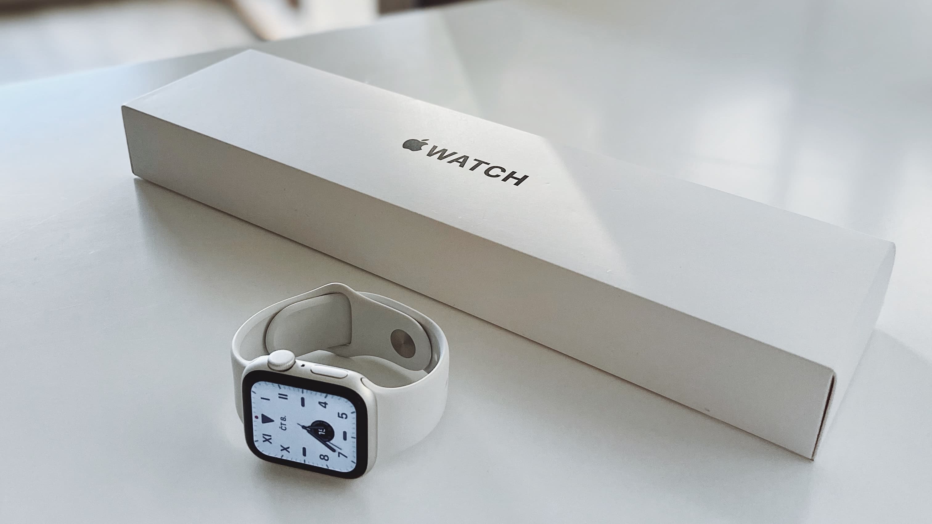 Apple Watch Series 7 rating on its side on a white table alongside its packaging