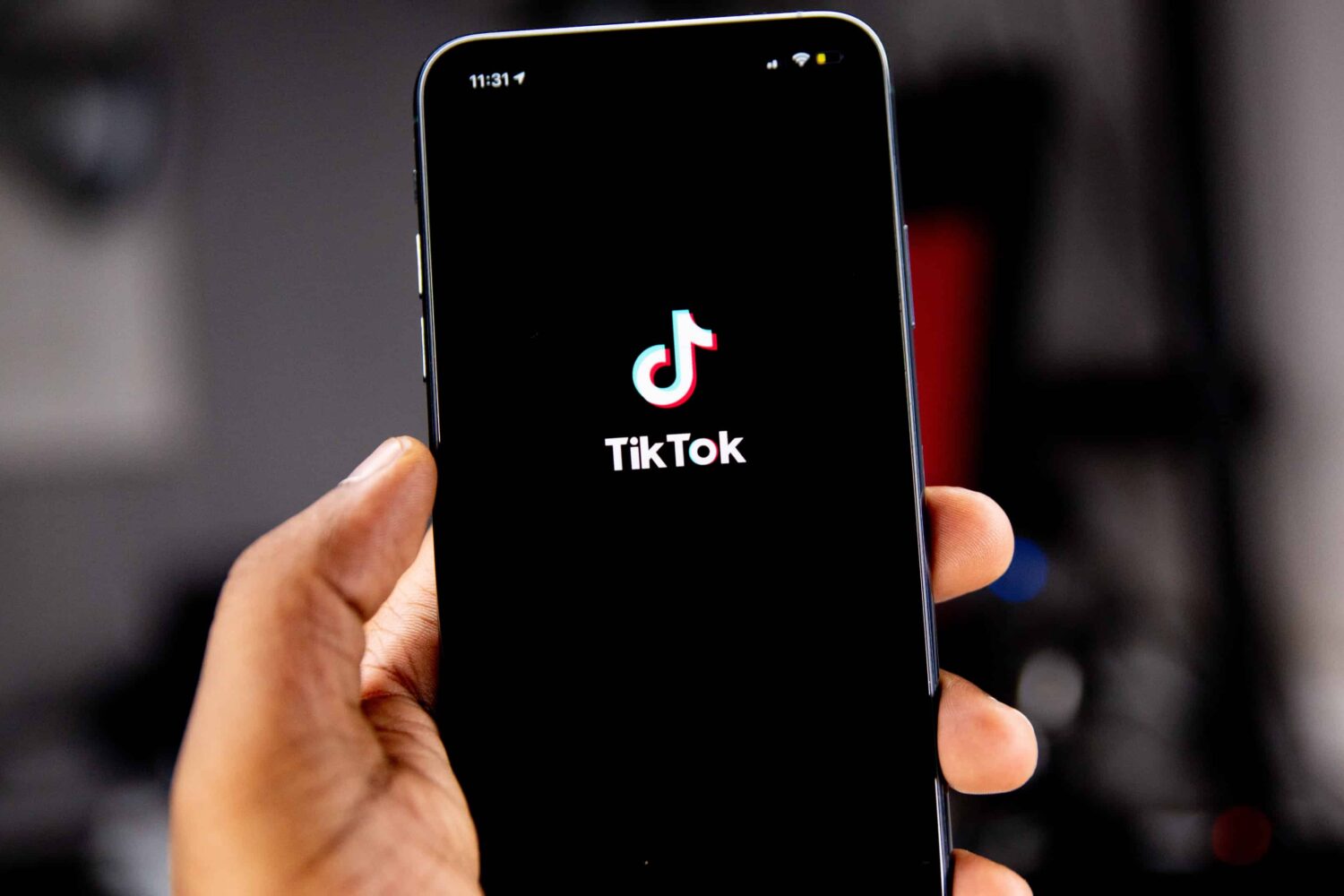 iPhone in hand showing launching the TikTok app