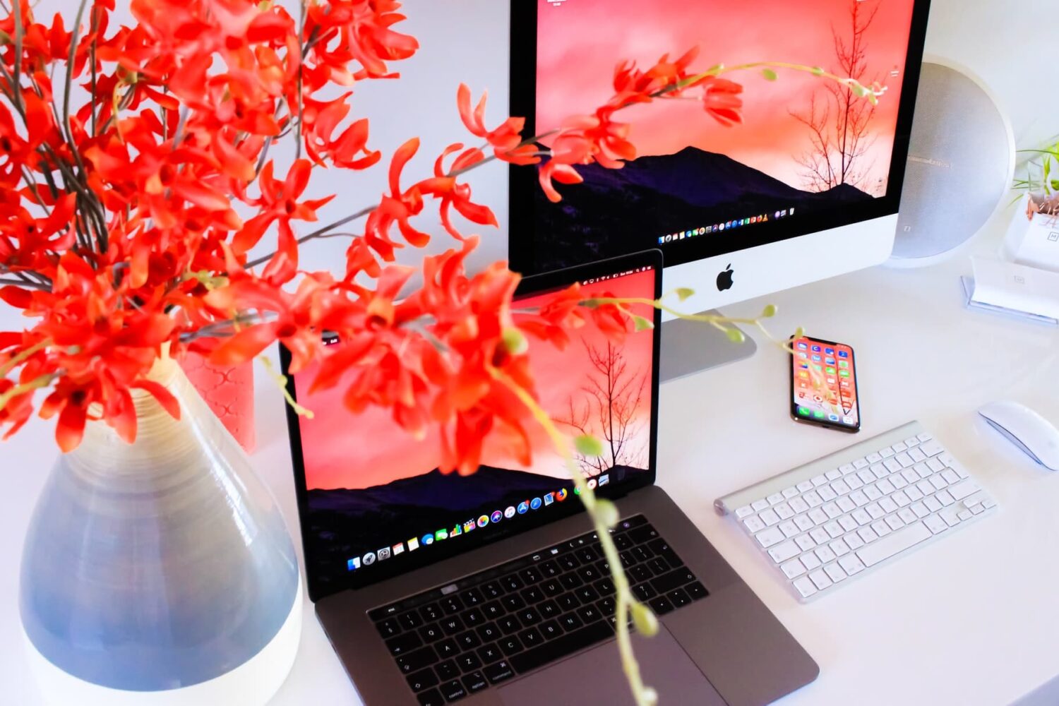 iPhone, MacBook, and an iMac kept on a desk