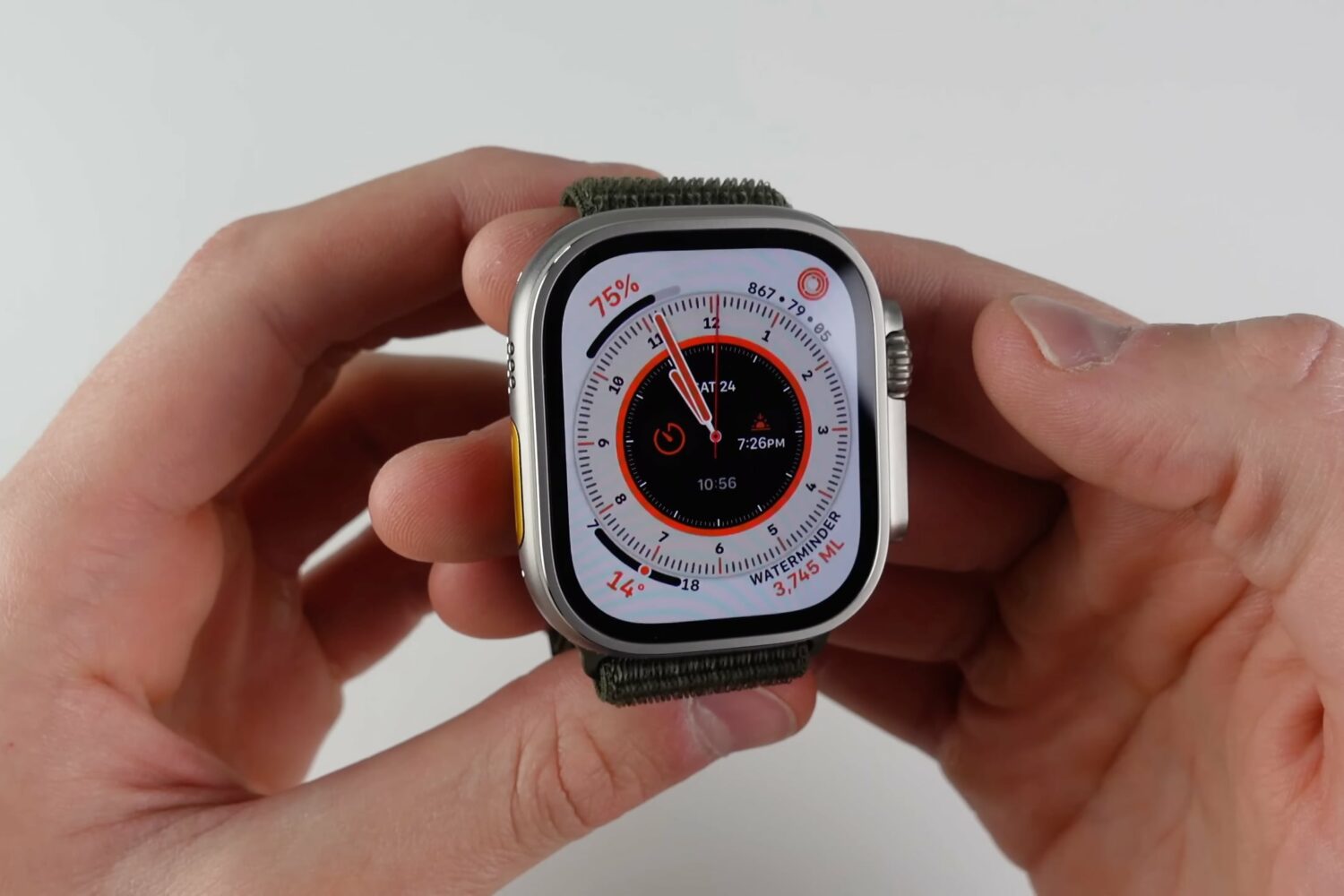 Apple Watch Ultra held in hands, displaying the Wayfinder watch face