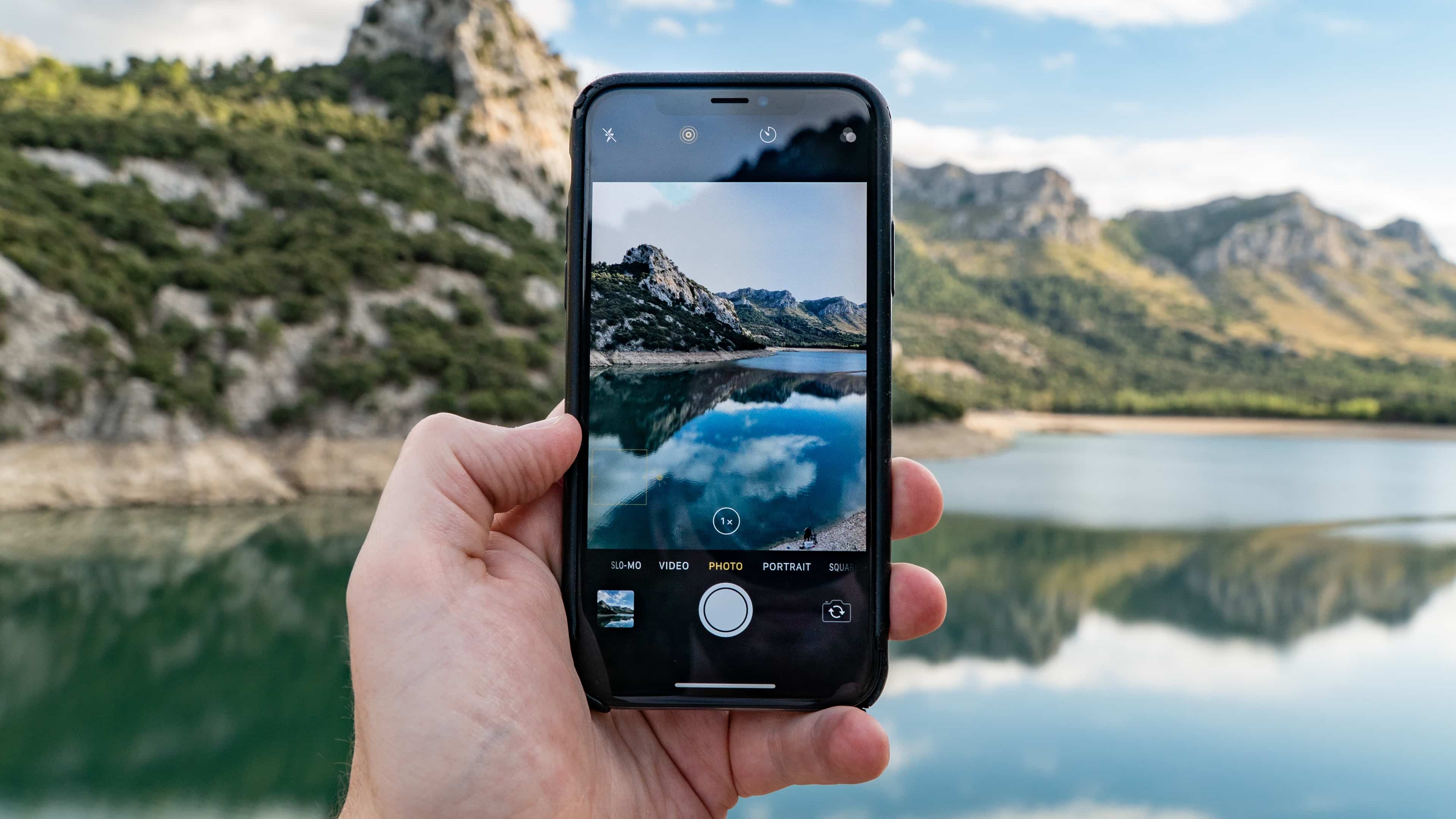 iPhone held in hand, with a scenic landscape capture with the Camera app