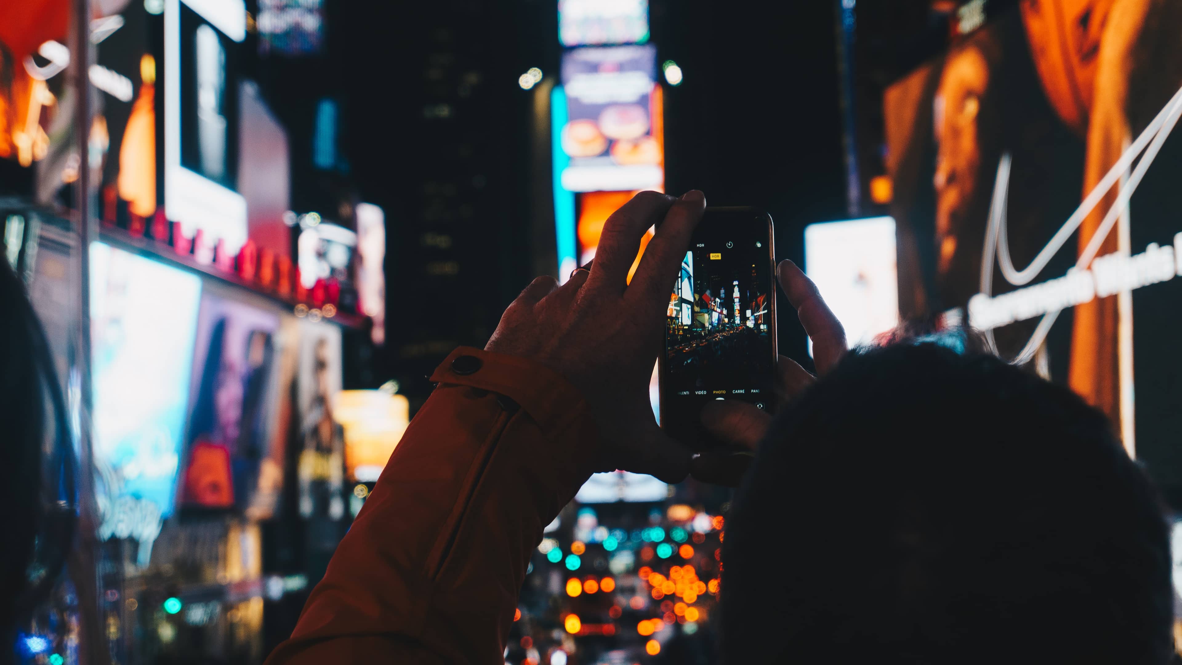 Man uses Apple's Camera app on his iPhone to photograph Times Square in New York