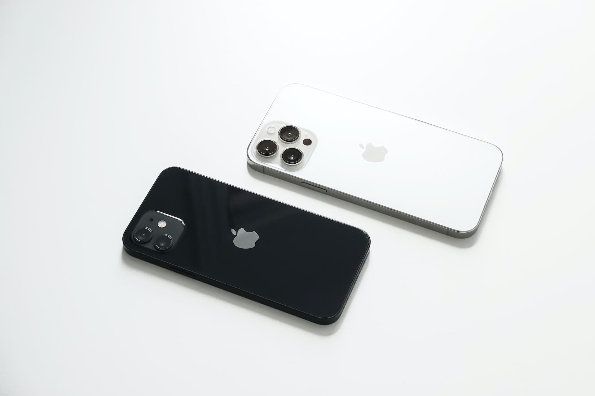 iPhone 12 in black color with two rear cameras and white iPhone 13 Pro with three back cameras kept together
