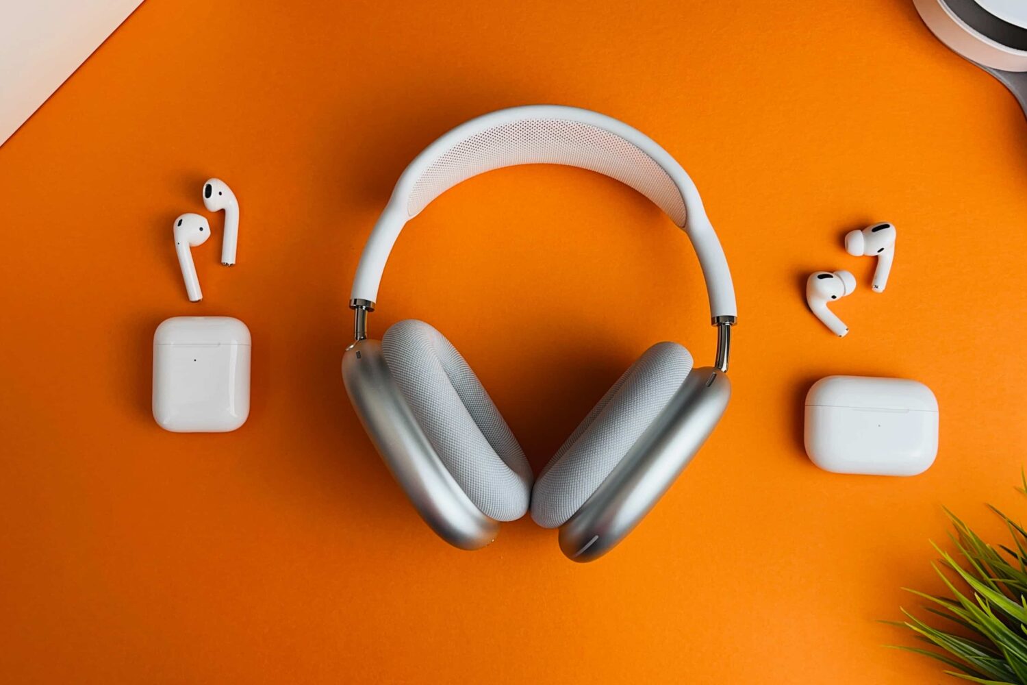 AirPods Max, the original AirPods and the first AirPods Pro laid flat on an orange table