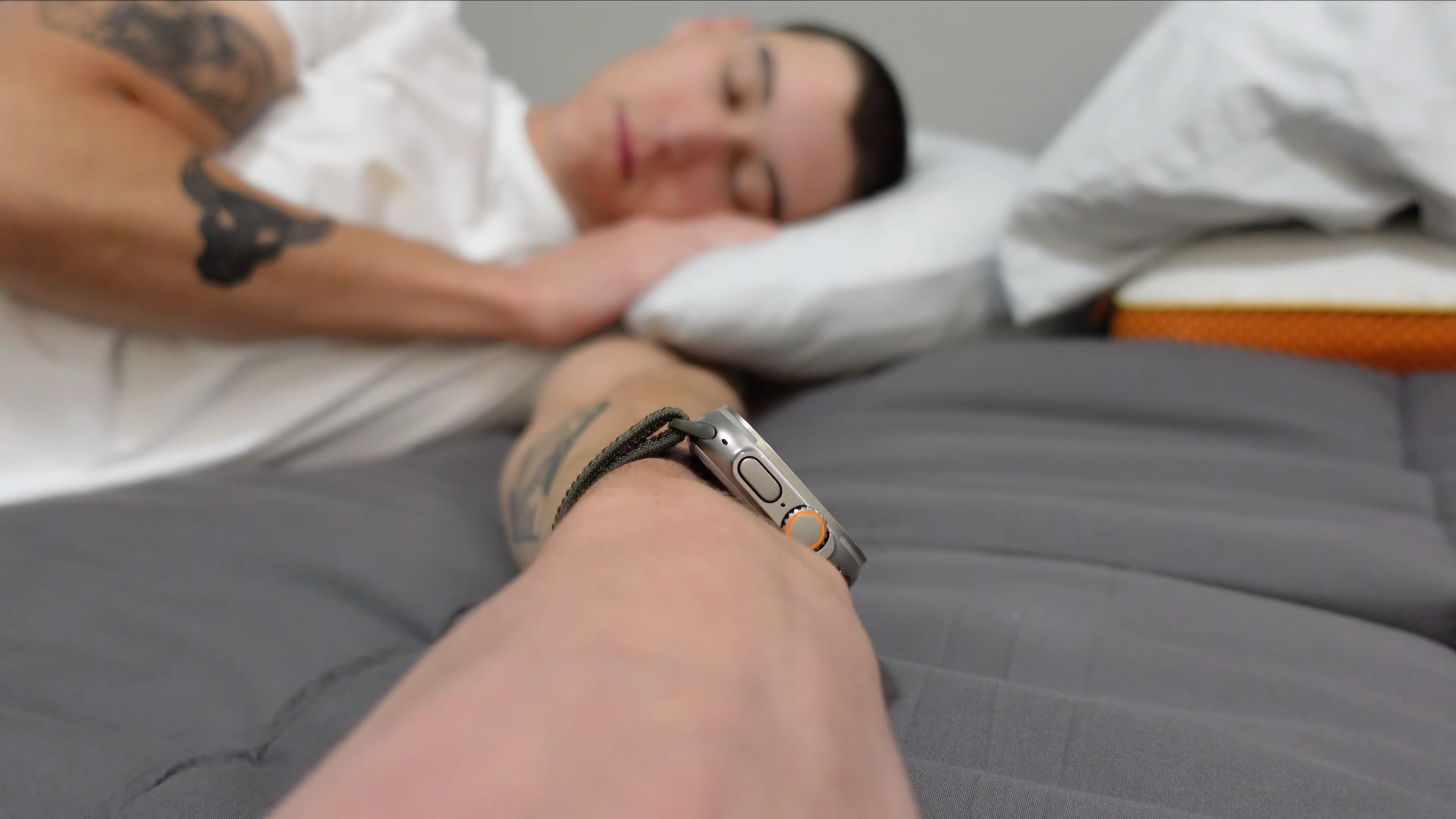 A young man sleeping in his bed, wearing Apple Watch Ultra on their wrist