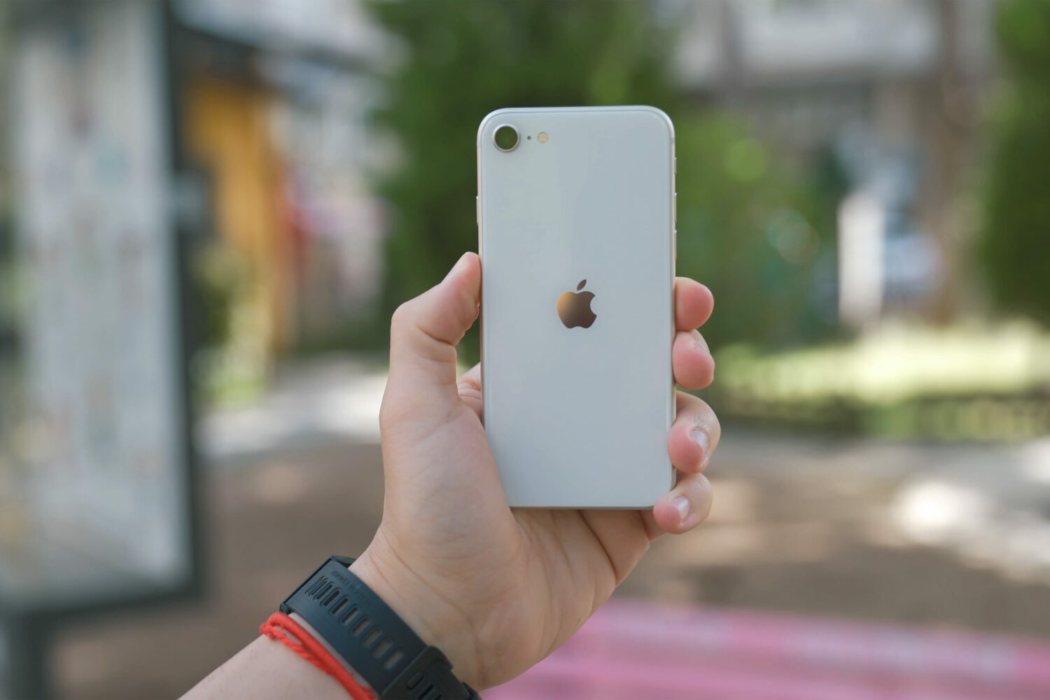A white third-generation iPhone SE held in hand, showcasing the back of the device