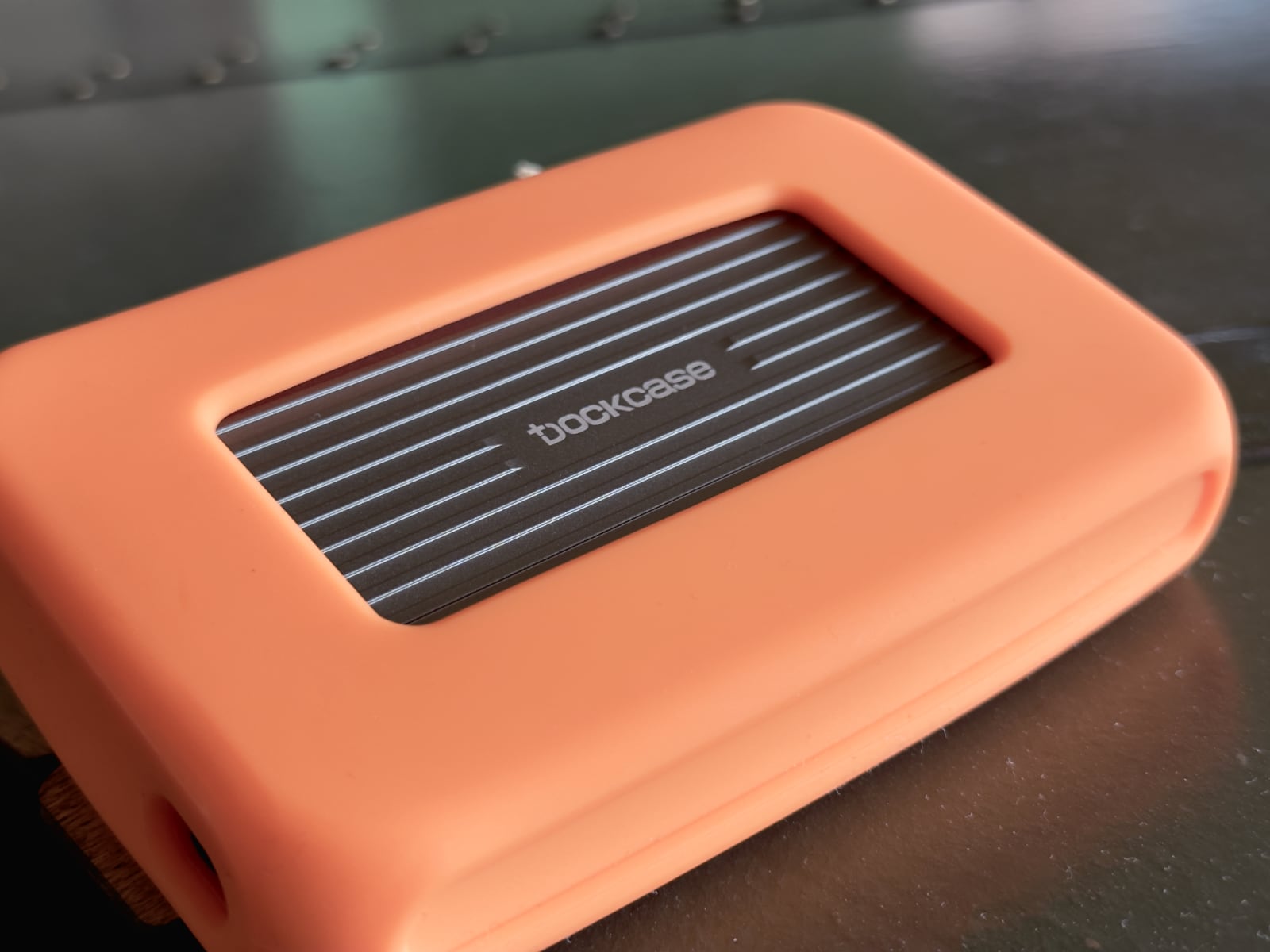 DockCase external storage enclosure in an orange protective case, sitting on a desk