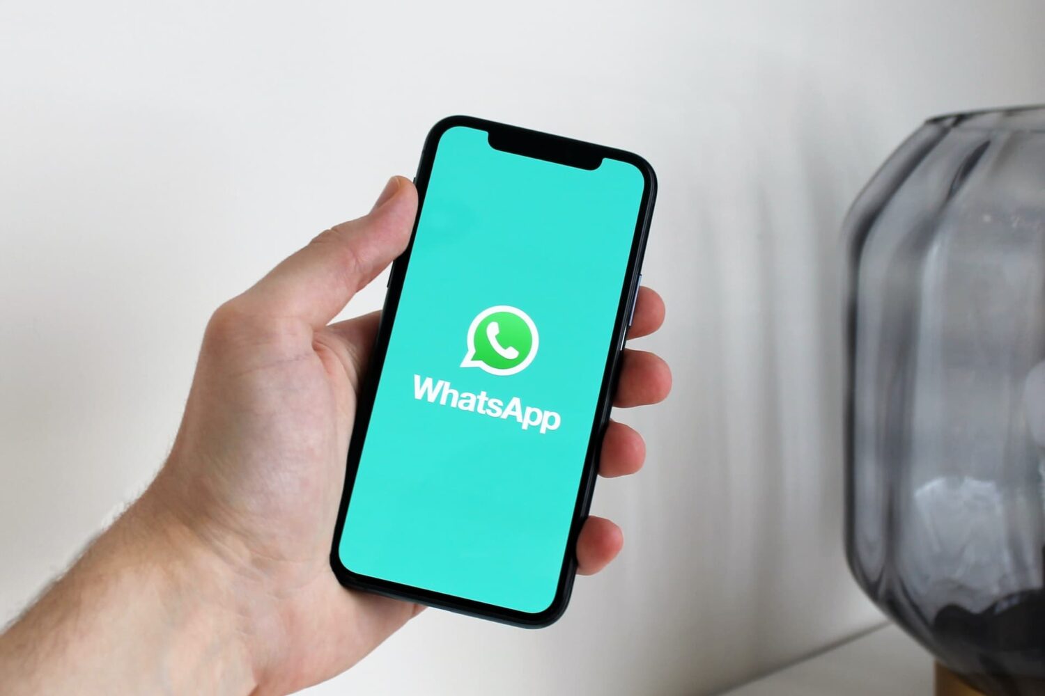 Holding iPhone in hand with WhatsApp logo on the screen