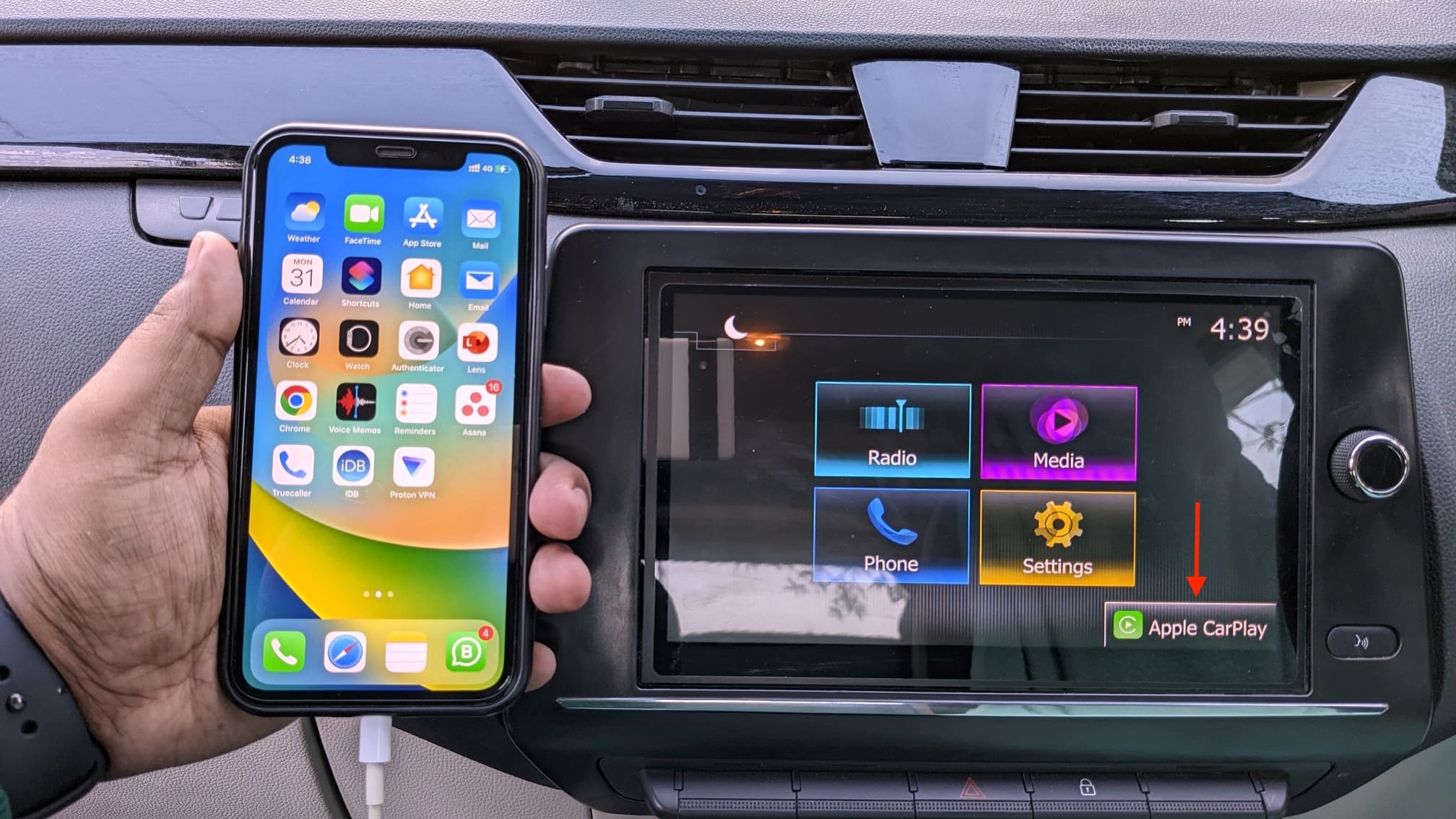 Apple CarPlay on car dashboard with connected iPhone in hand