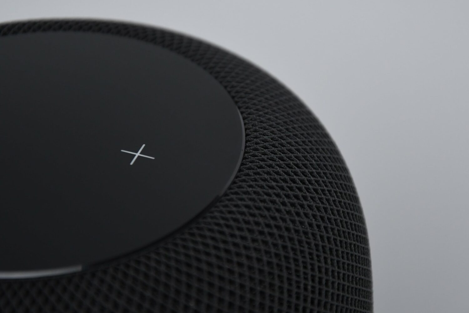 Closeup showing the volume up button on the touch surface of a black HomePod smart speaker