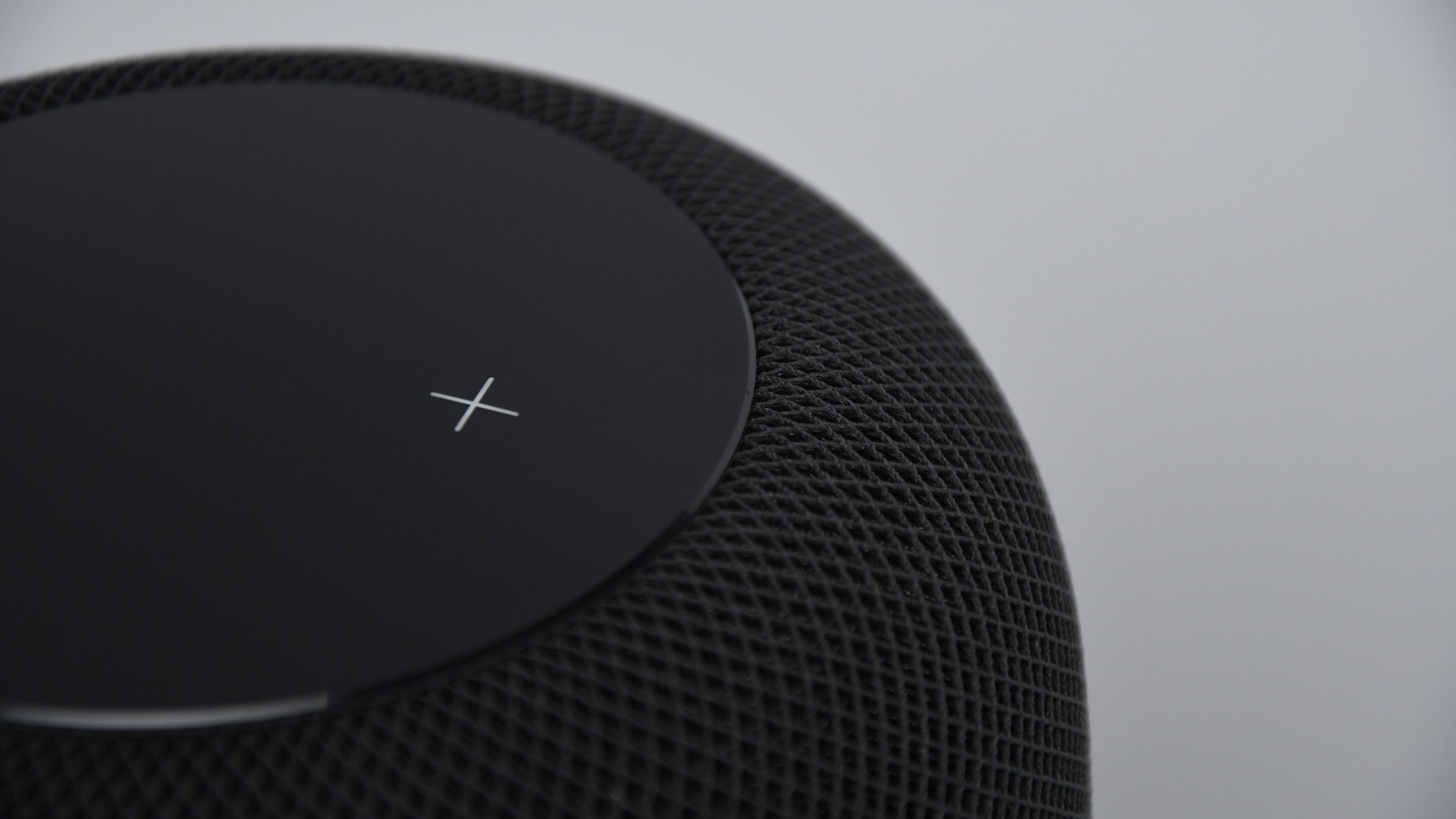 Closeup showing the volume up button on the touch surface of a black HomePod smart speaker 