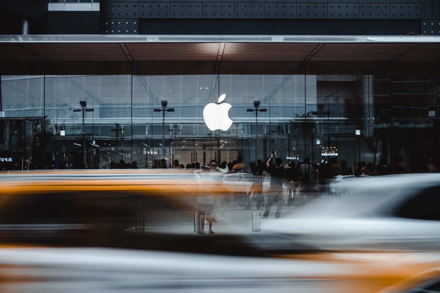 Exterior of Apple's retail store in Taipei's A13 Xinyi district with passing cars on the street shot with long exposure to appear blurred as if speeding